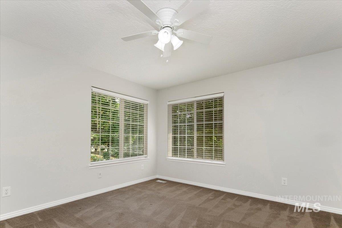 Empty room with carpet floors, a textured ceiling, and a ceiling fan