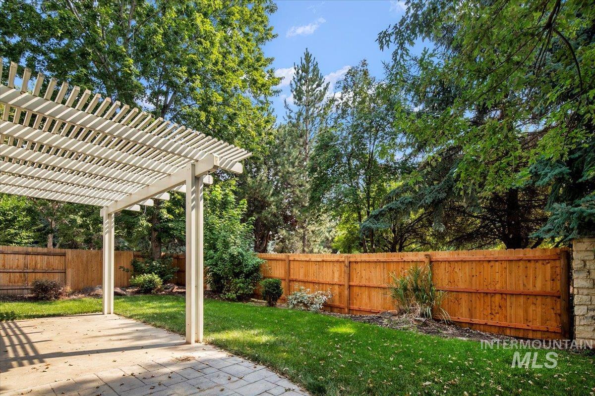 Fenced backyard with a pergola, a patio area, and view of wooded area