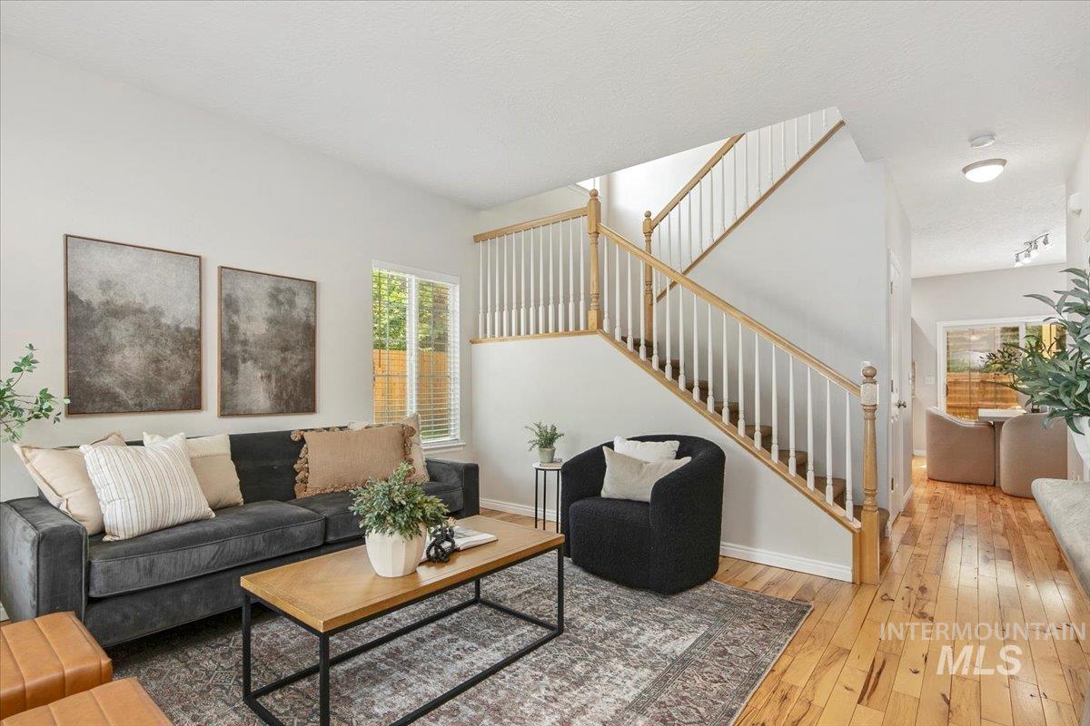 Living area with stairs, hardwood / wood-style floors, and a textured ceiling