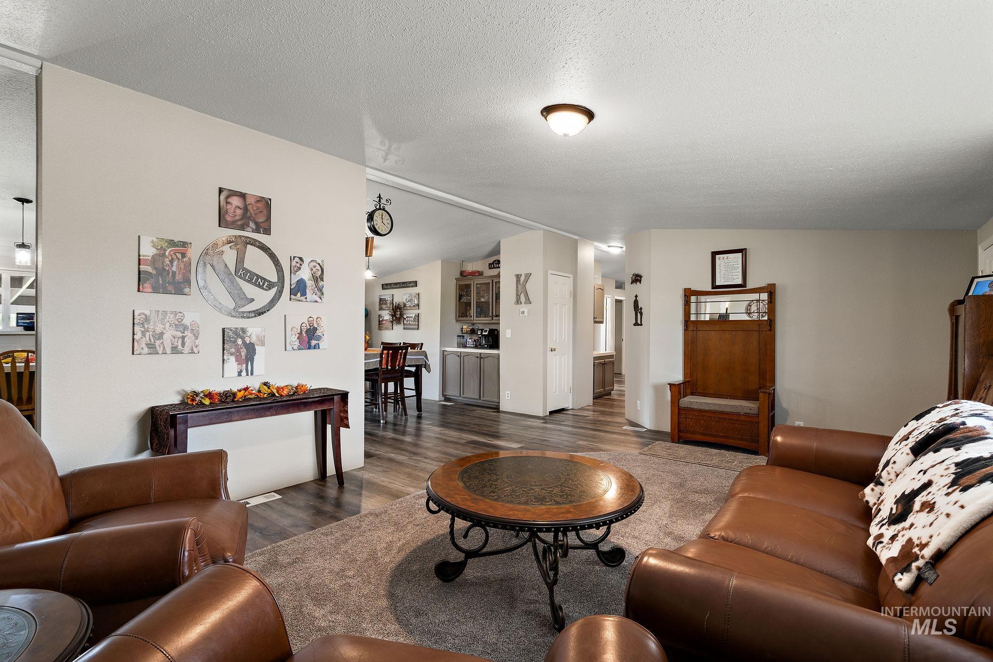 Living area with dark wood finished floors, a textured ceiling, and vaulted ceiling