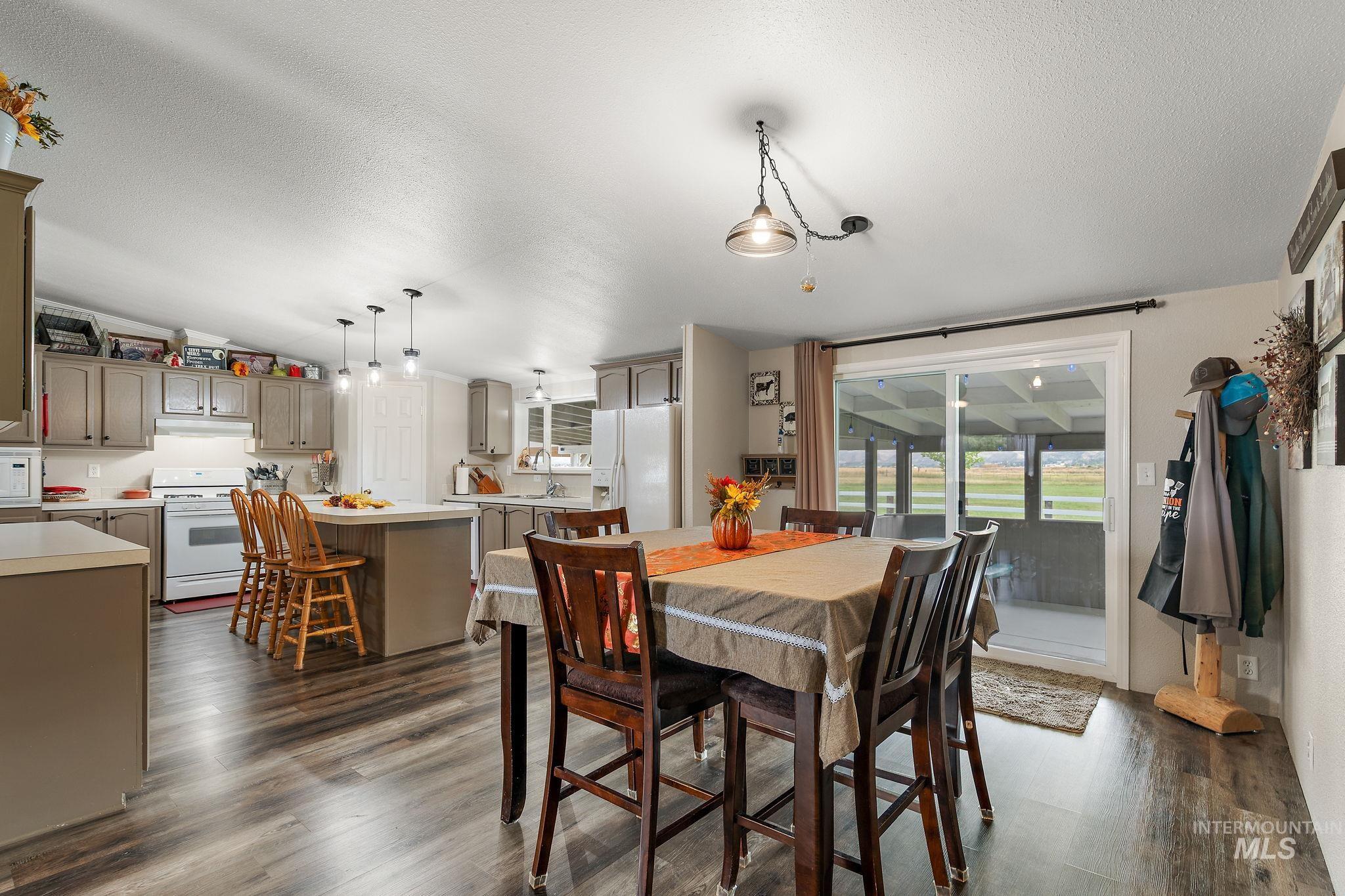 Dining area featuring dark wood-type flooring, a textured ceiling, and vaulted ceiling