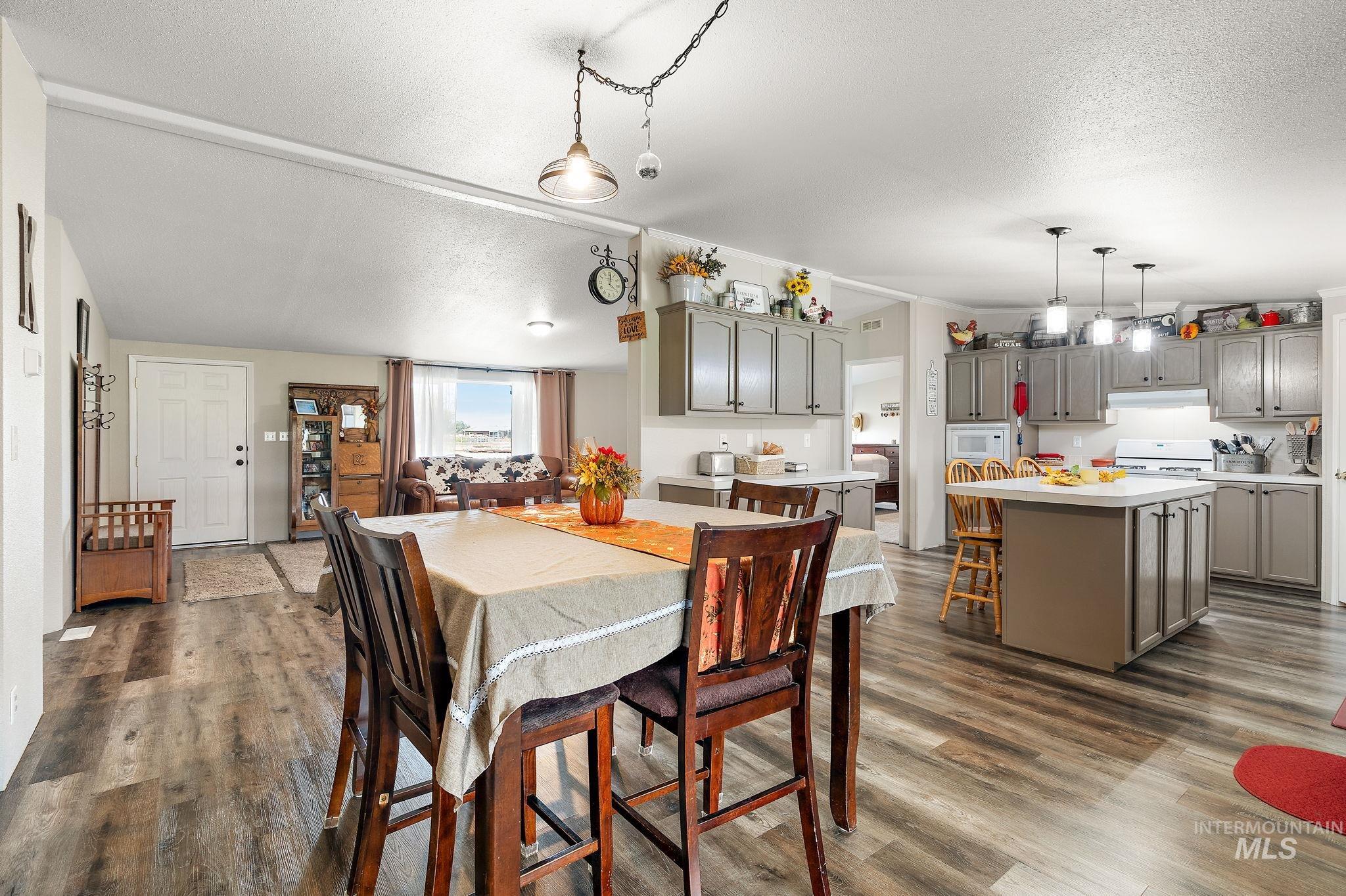 Dining space with a textured ceiling, dark wood-type flooring, and lofted ceiling