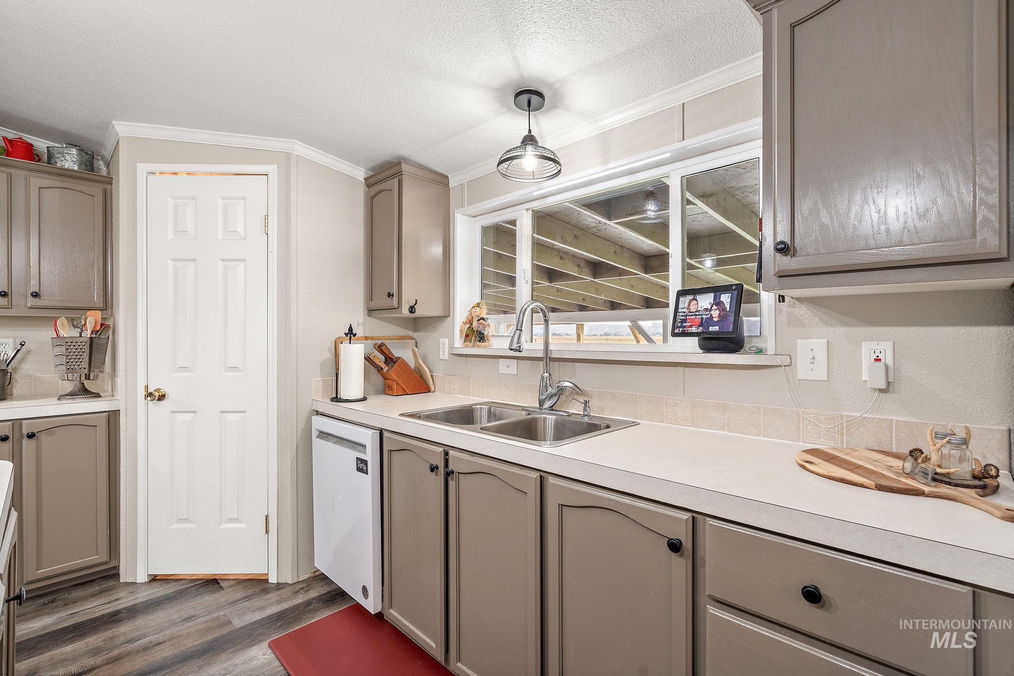 Kitchen featuring gray cabinetry, crown molding, dark wood-type flooring, light countertops, and a textured ceiling