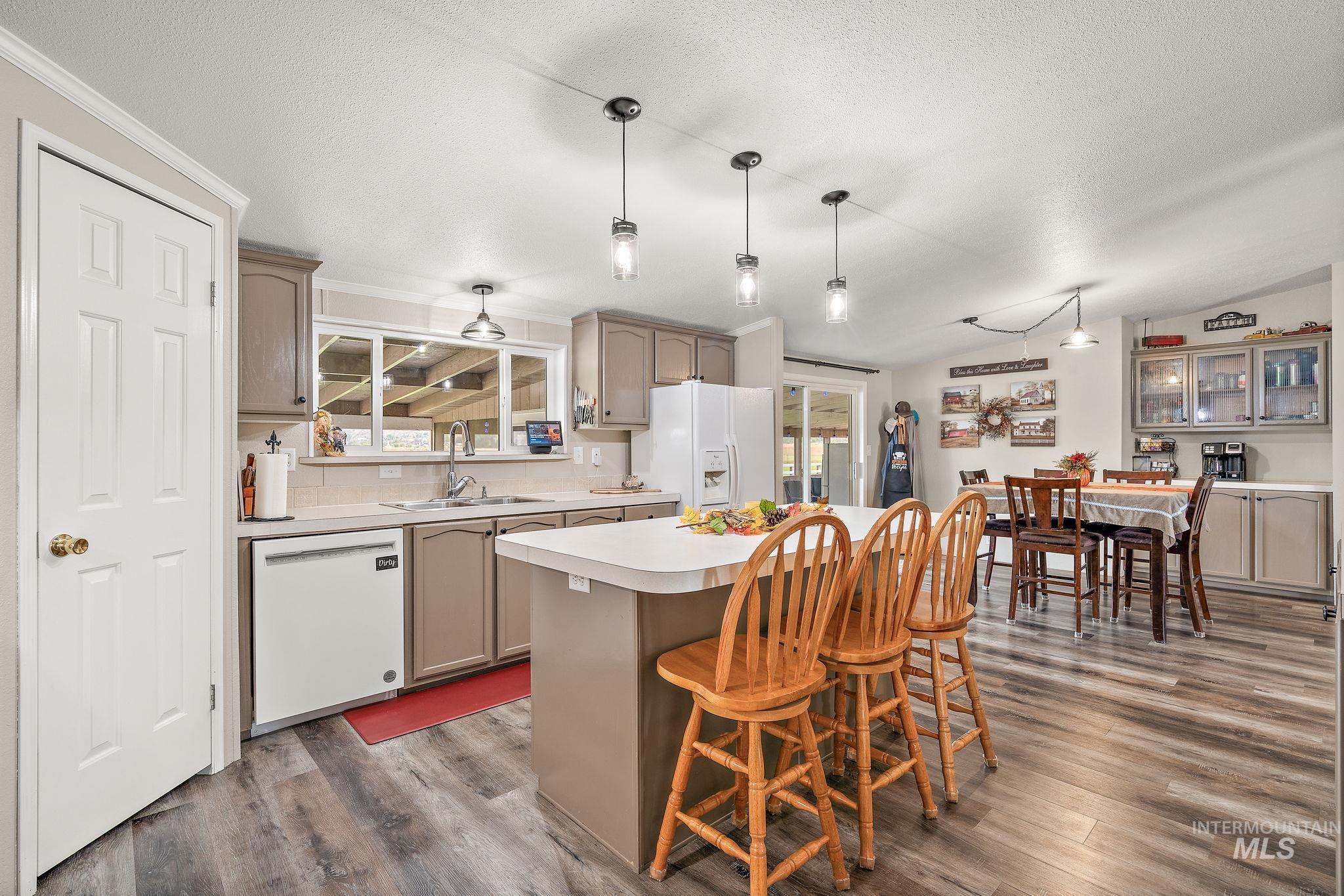 Kitchen featuring hanging light fixtures, light countertops, a center island, healthy amount of natural light, and lofted ceiling