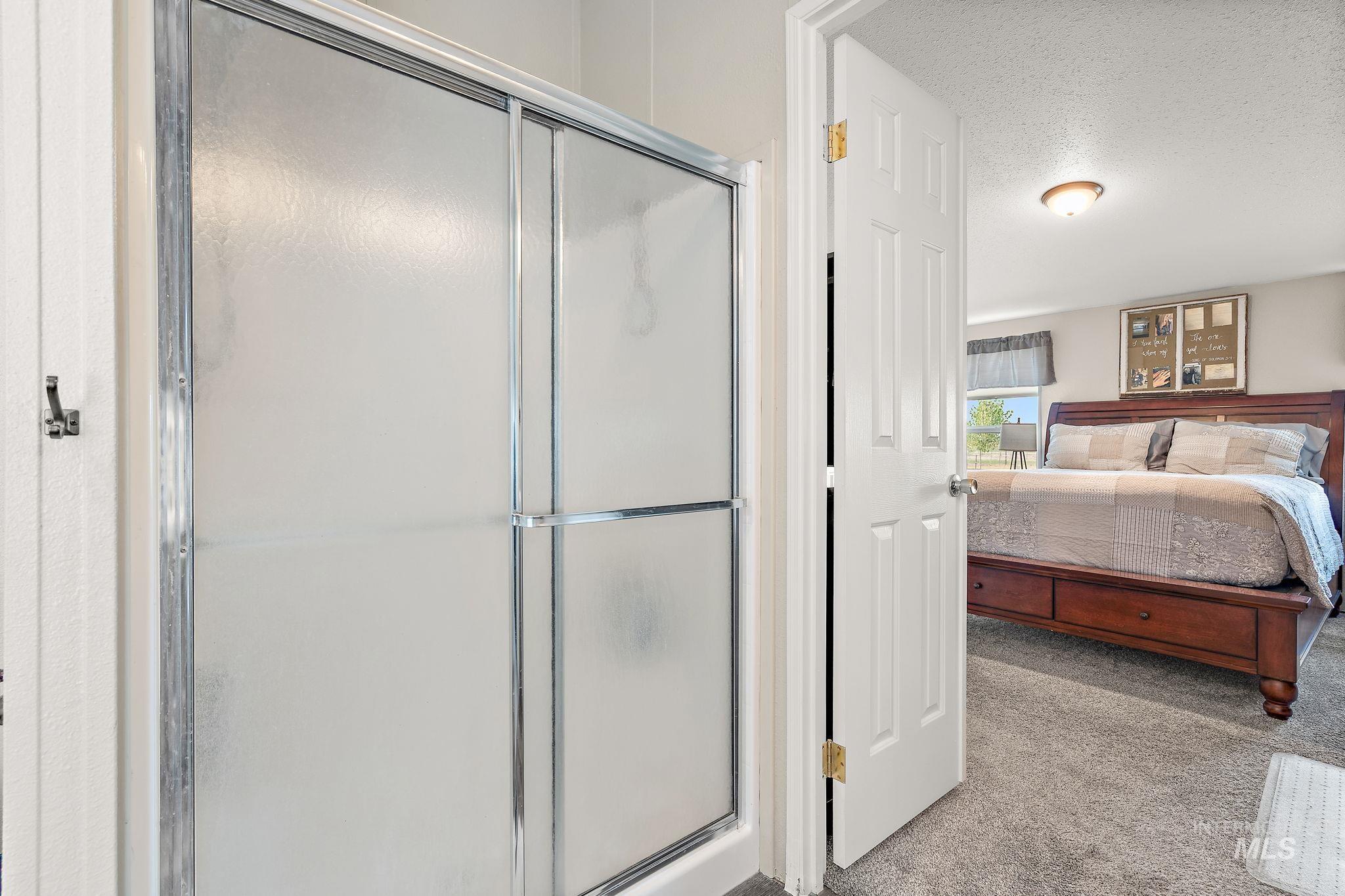 Ensuite bathroom featuring a textured ceiling and a stall shower