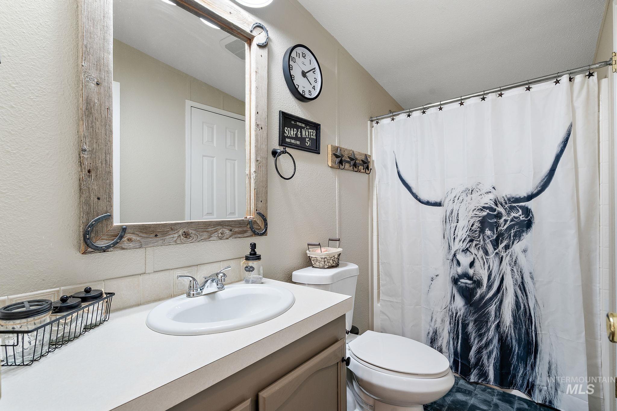 Full bathroom featuring vanity, a textured wall, and curtained shower