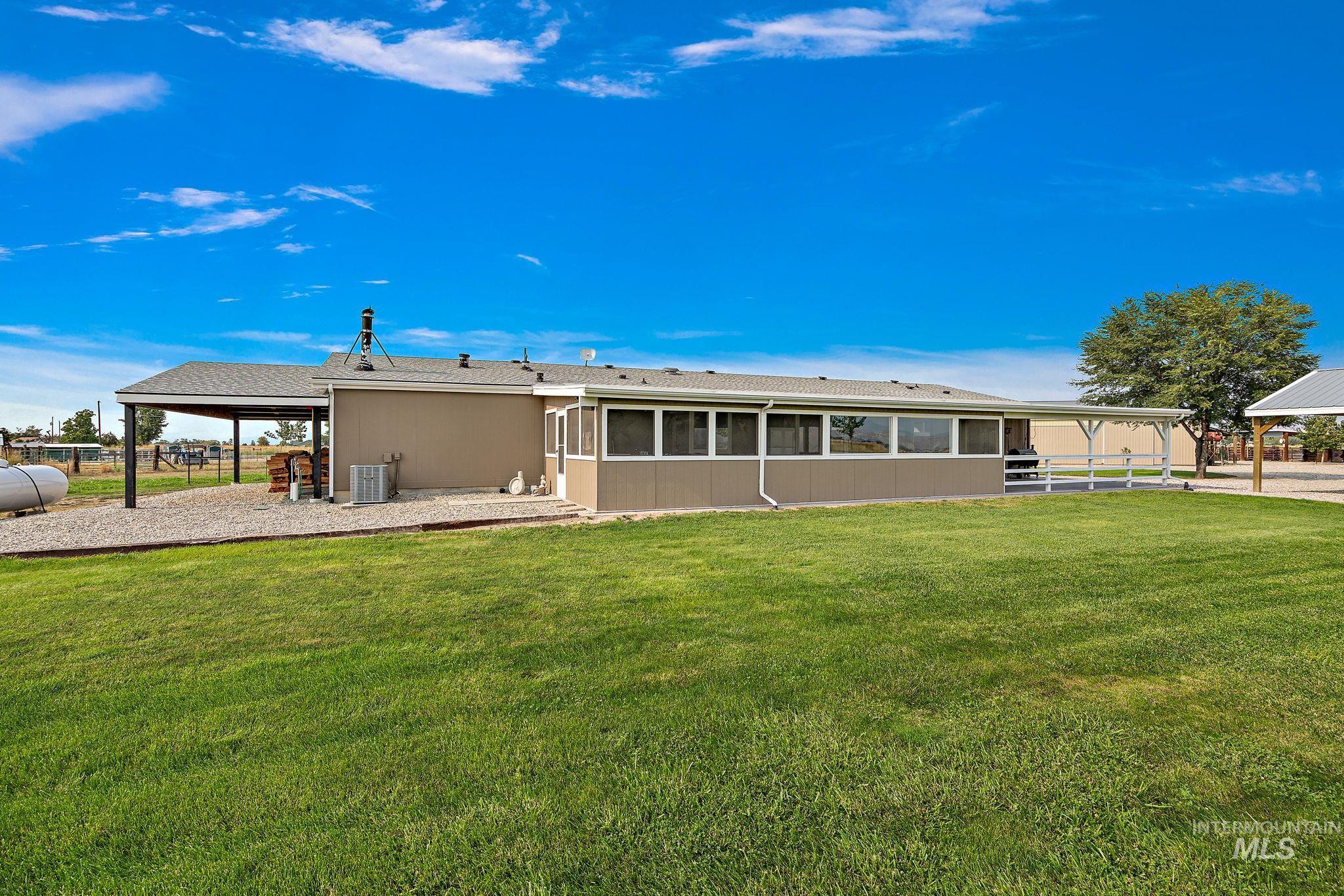 Back of house featuring roof with shingles, a yard, a sunroom, and a patio area