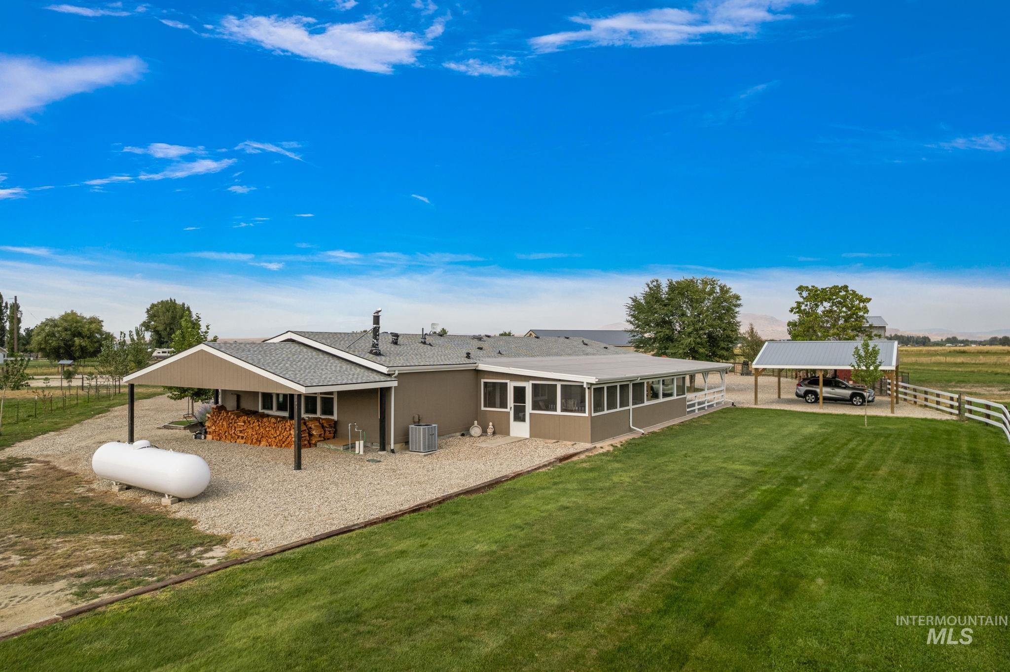 Back of house featuring a sunroom, a patio area, and roof with shingles