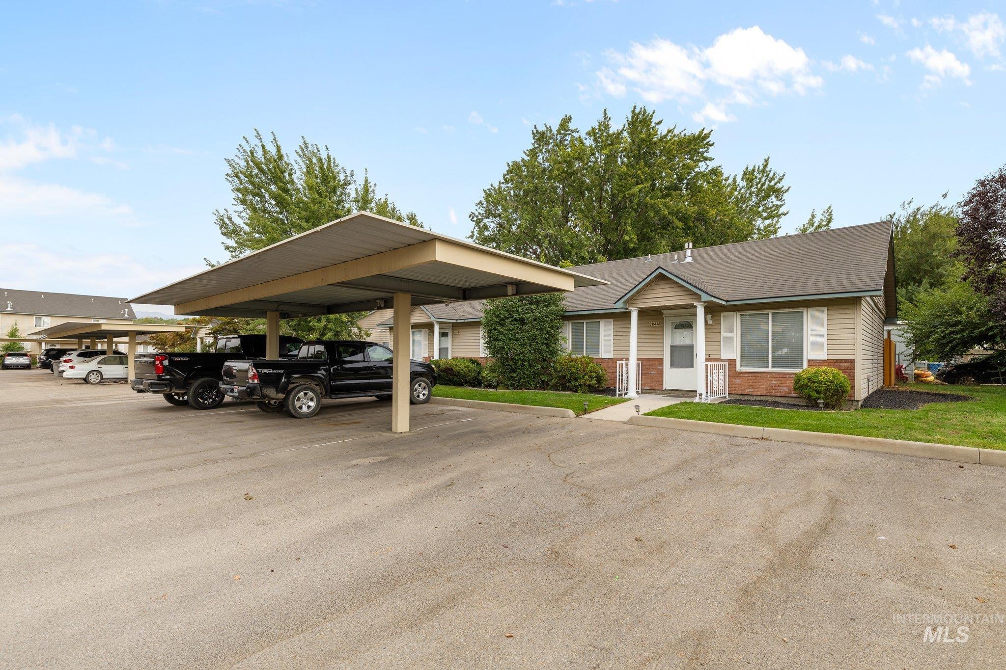 View of front of home featuring covered and uncovered parking and brick siding