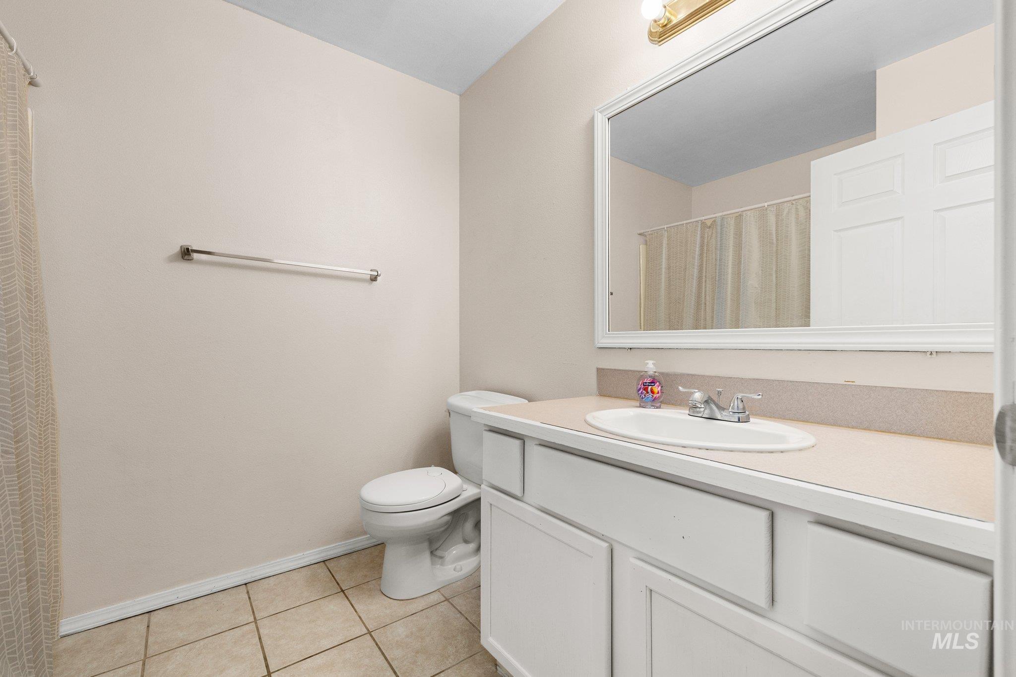 Bathroom featuring vanity, light tile patterned floors, and curtained shower