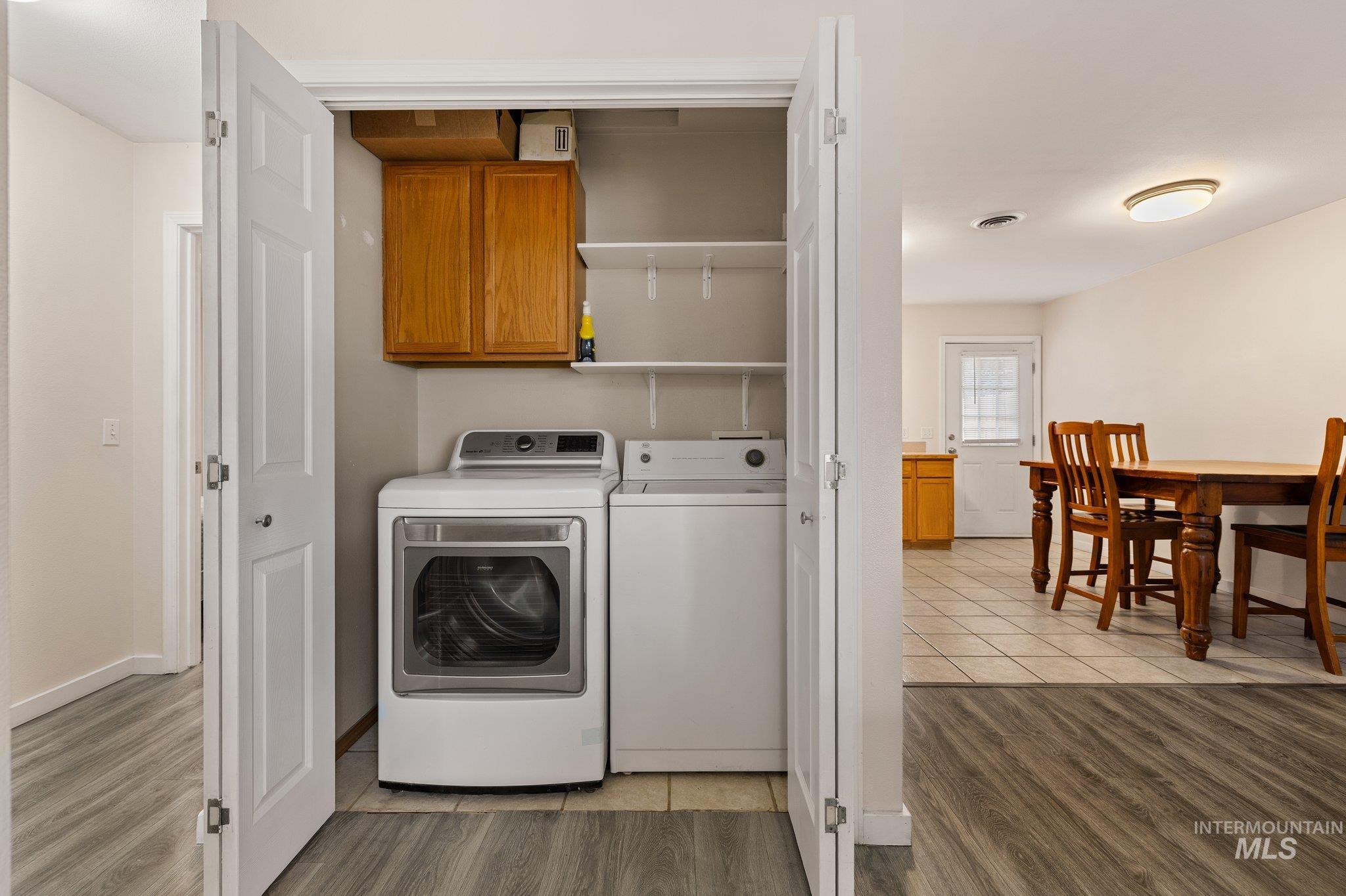 Laundry room featuring light wood finished floors, washing machine and clothes dryer, and cabinet space