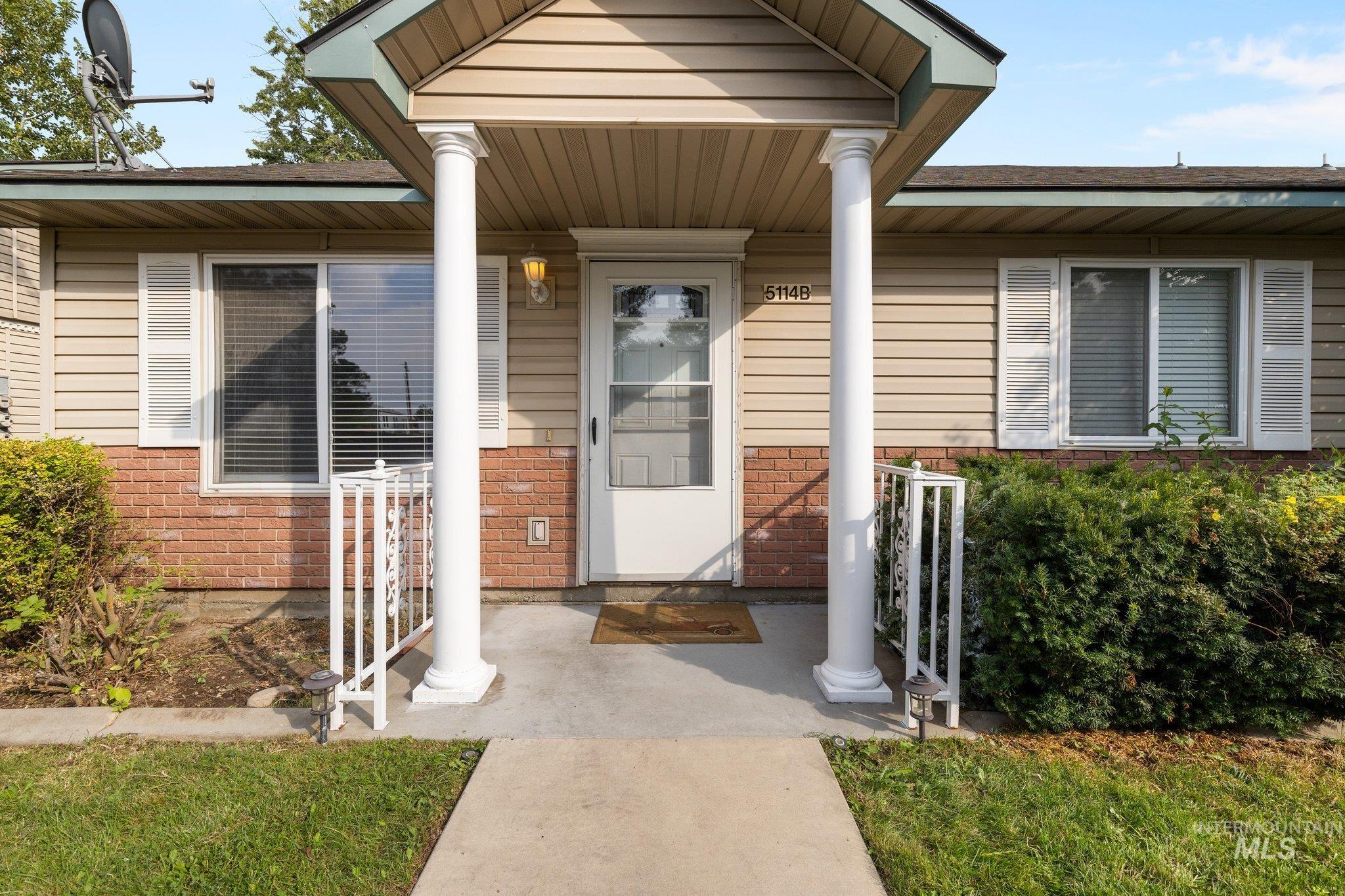 Entrance to property featuring brick siding, a porch, and a shingled roof