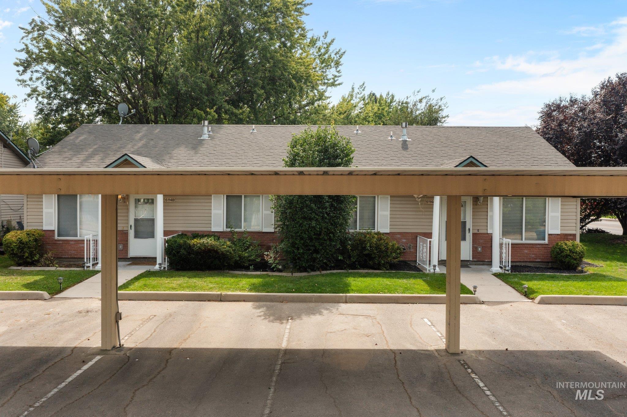 Ranch-style house with brick siding, roof with shingles, uncovered parking, and a front yard
