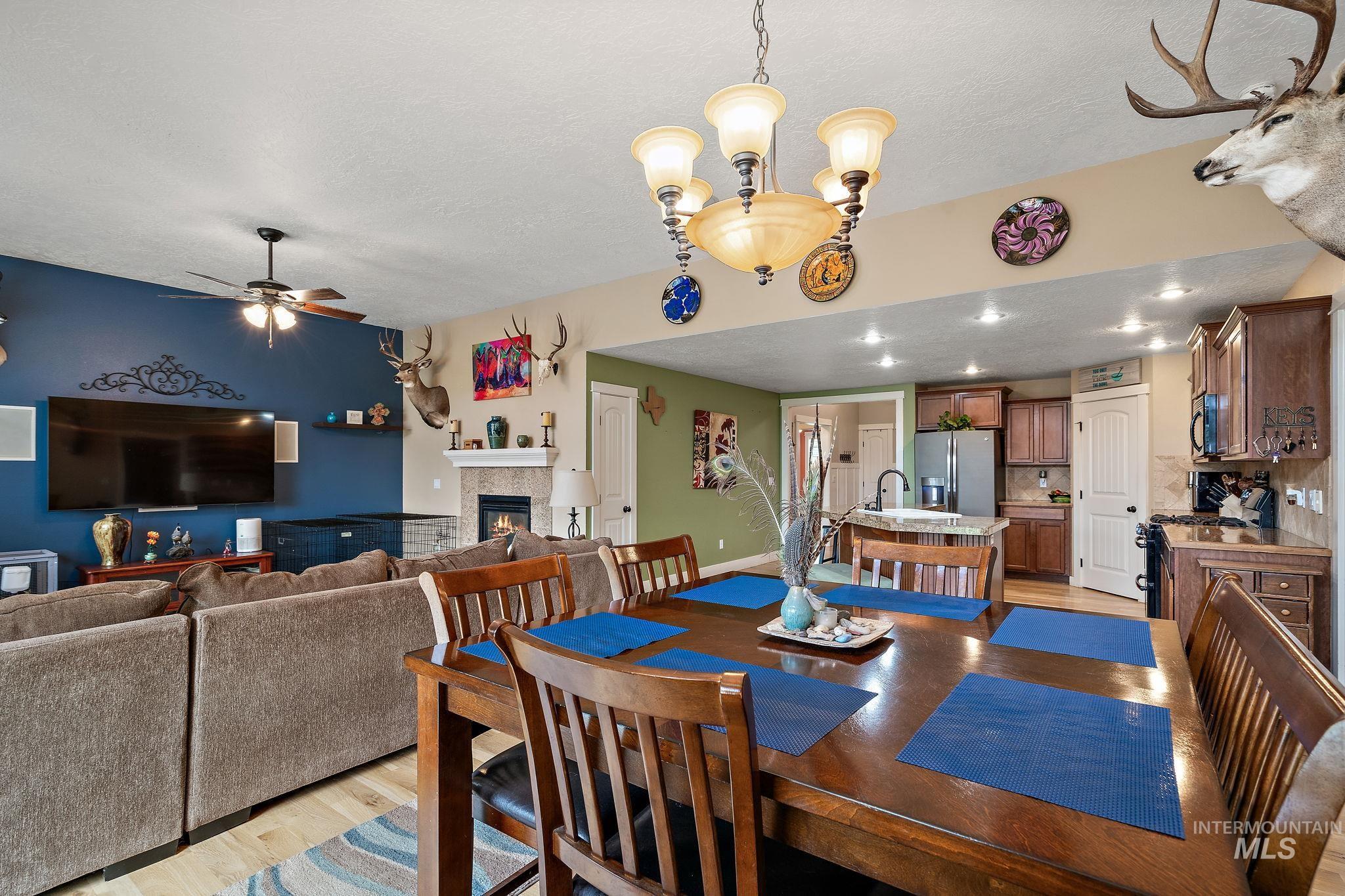 Dining area featuring light wood-style flooring, a tile fireplace, ceiling fan, a textured ceiling, and recessed lighting