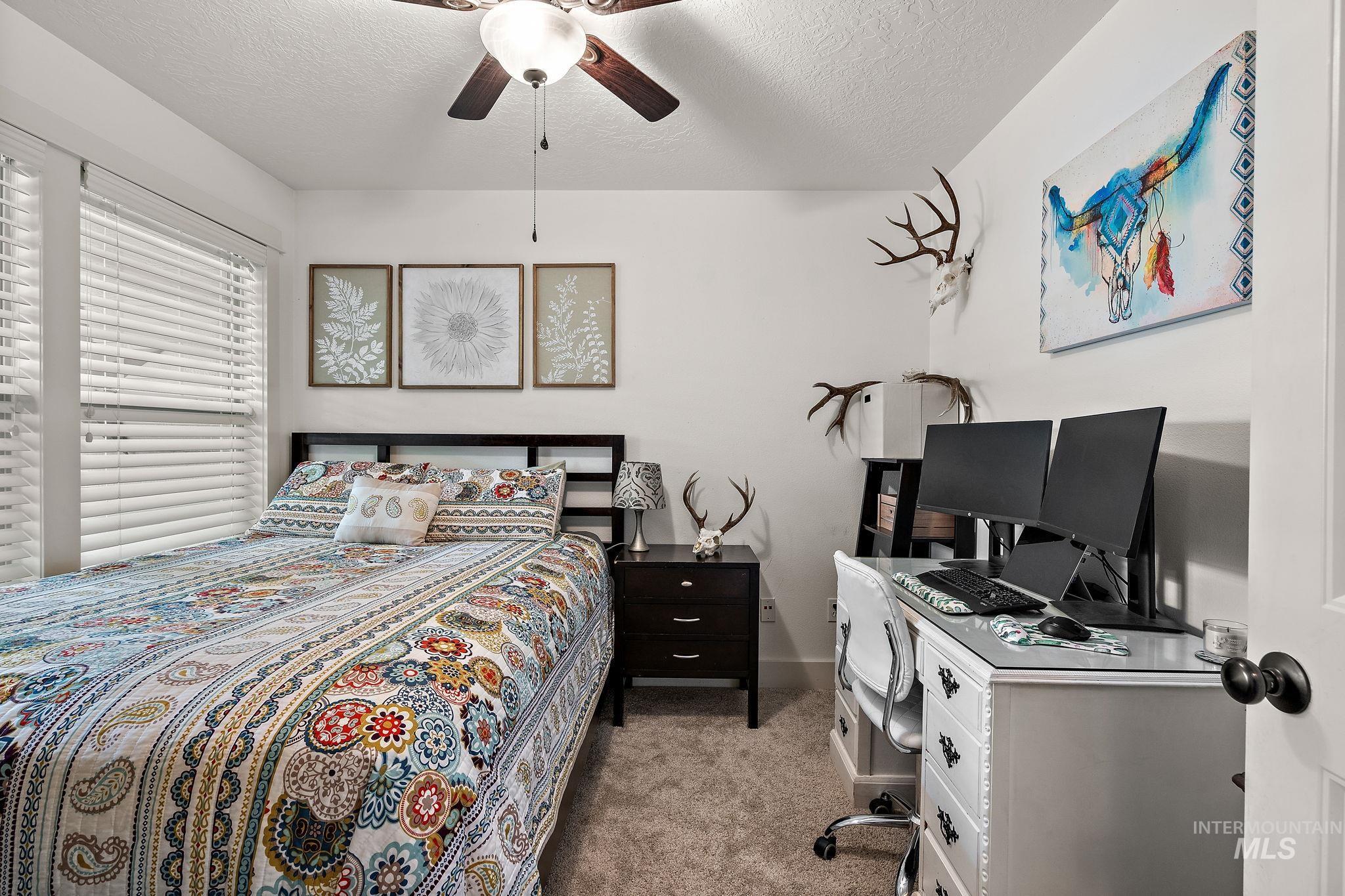 Bedroom with a textured ceiling, carpet, and a ceiling fan