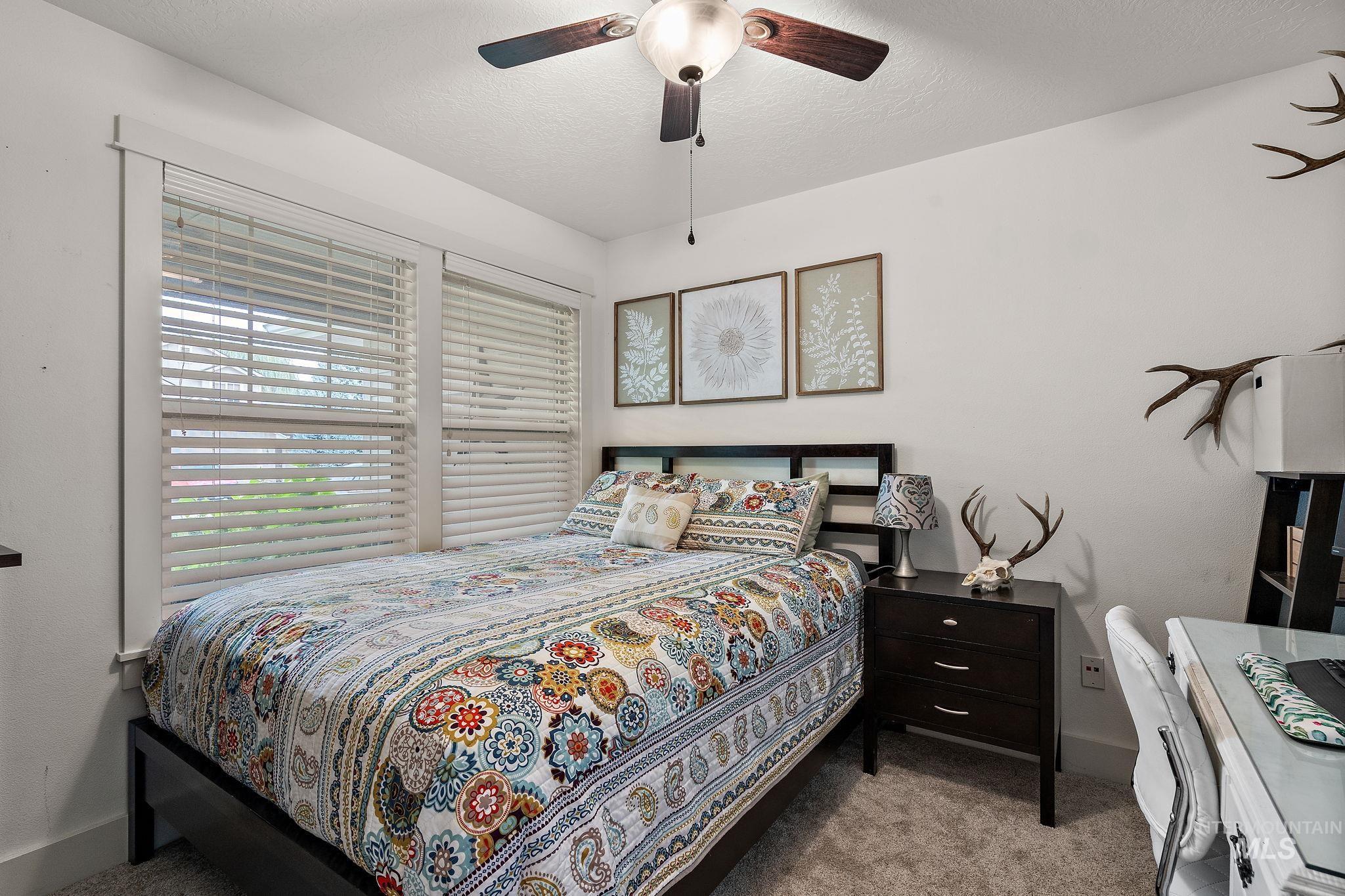 Bedroom with light colored carpet, a ceiling fan, and a textured ceiling