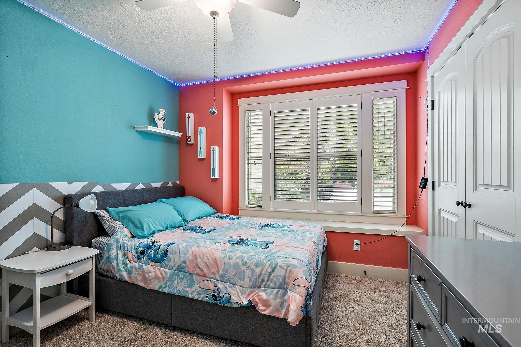 Carpeted bedroom featuring a textured ceiling, a closet, and a ceiling fan
