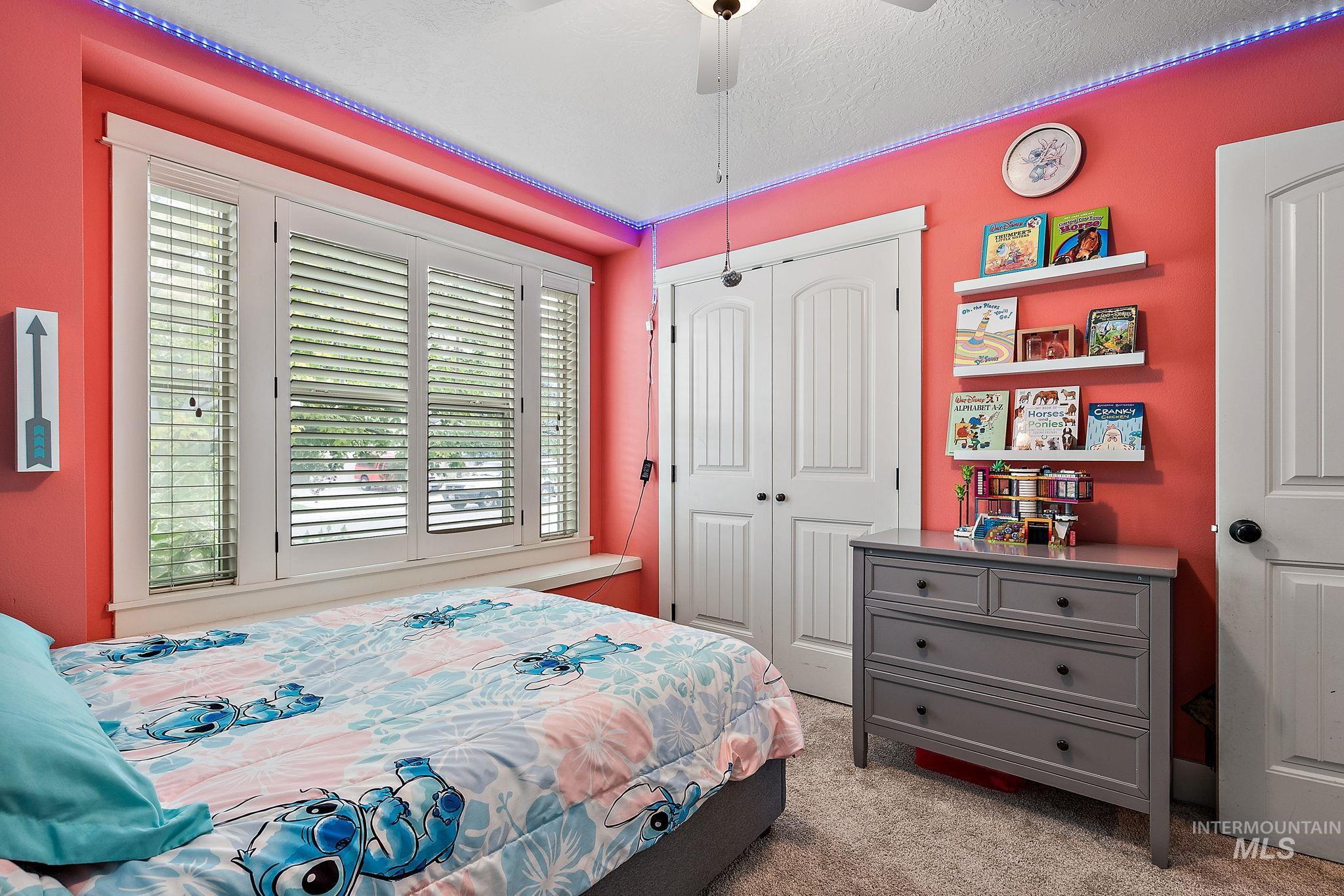 Bedroom featuring light colored carpet, ceiling fan, a closet, and a textured ceiling