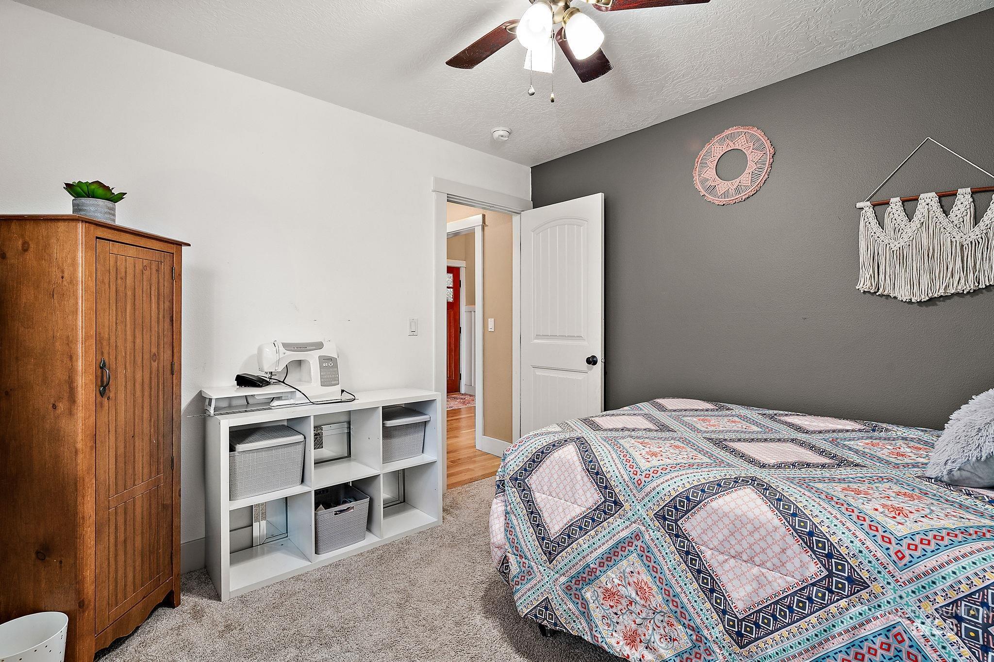 Bedroom with light carpet, a textured ceiling, and a ceiling fan