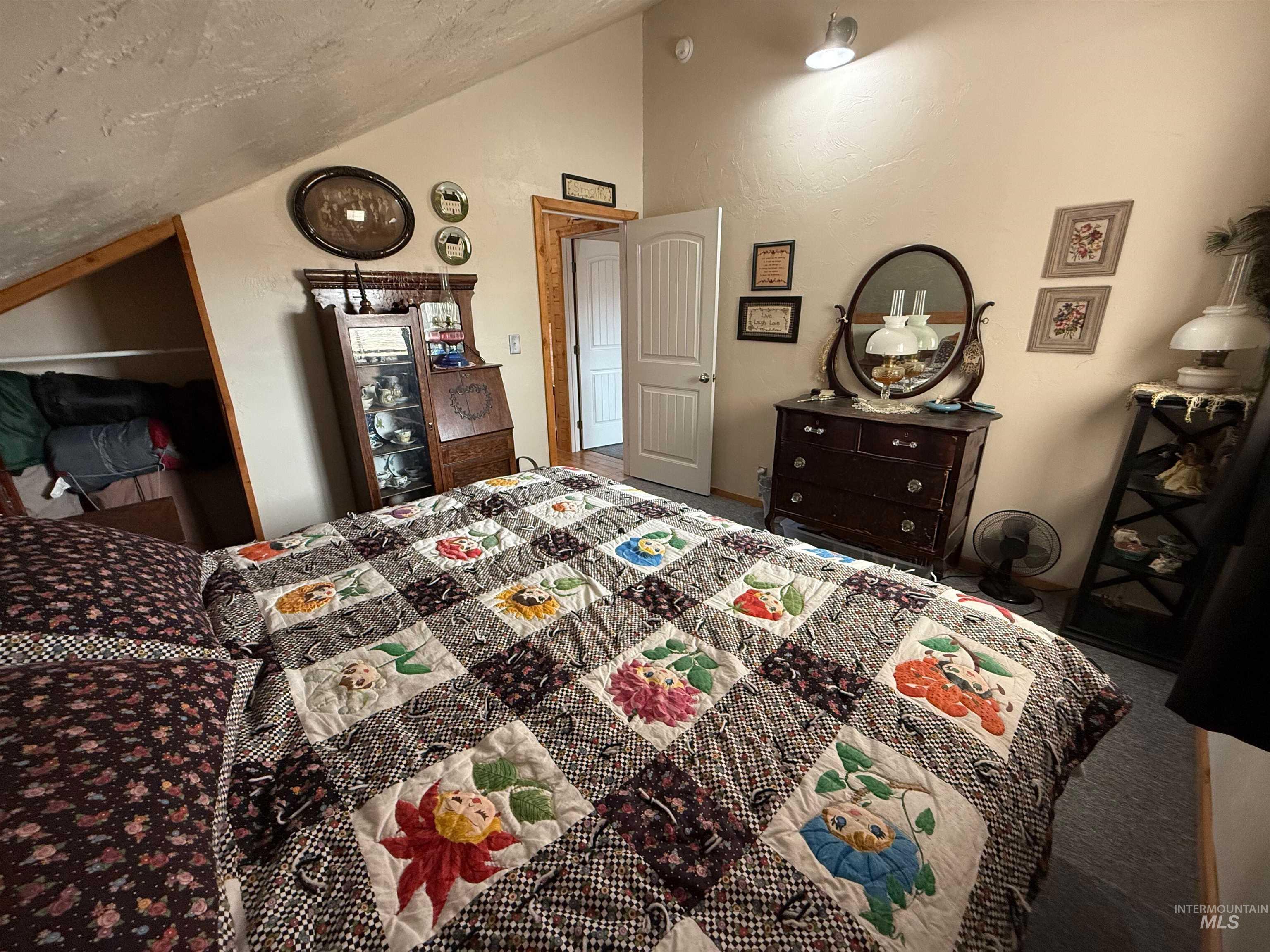 Carpeted bedroom featuring lofted ceiling and a textured ceiling