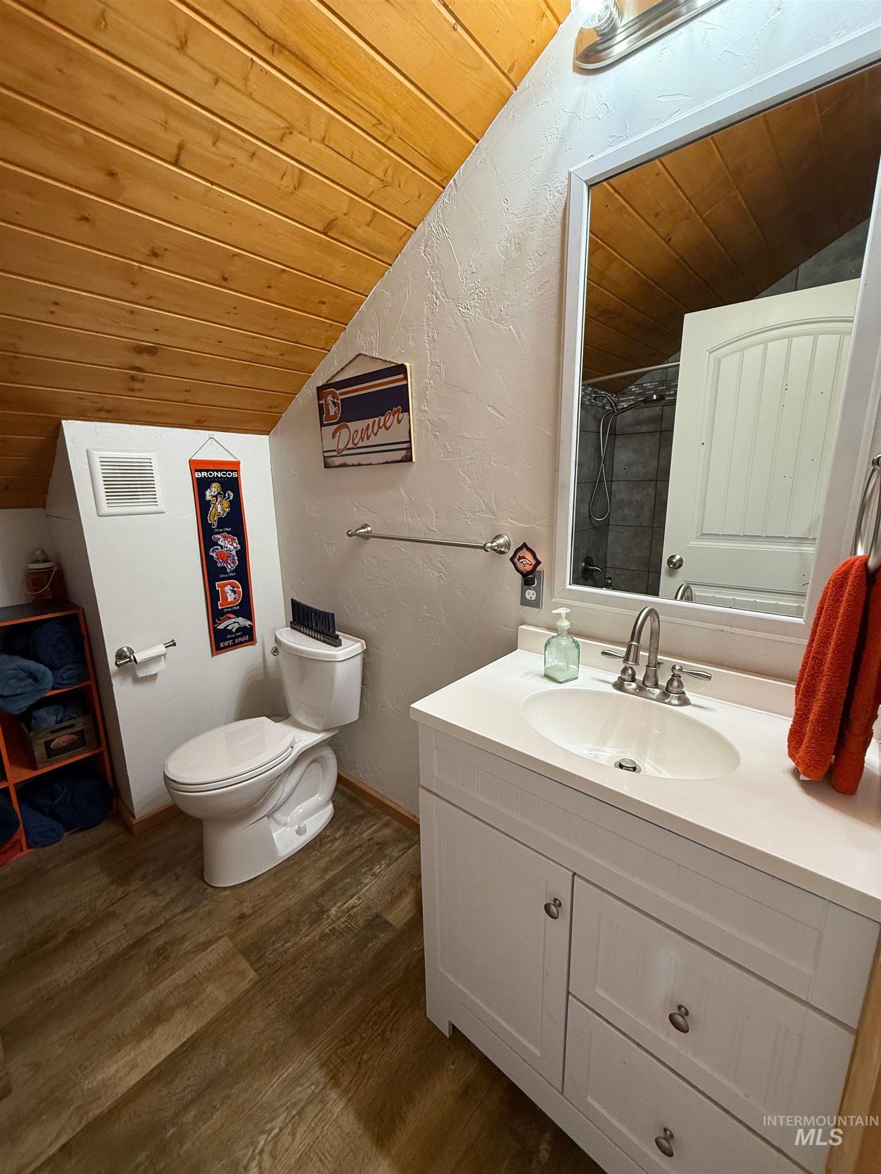 Full bathroom featuring a textured wall, wooden ceiling, lofted ceiling, dark wood-style floors, and vanity