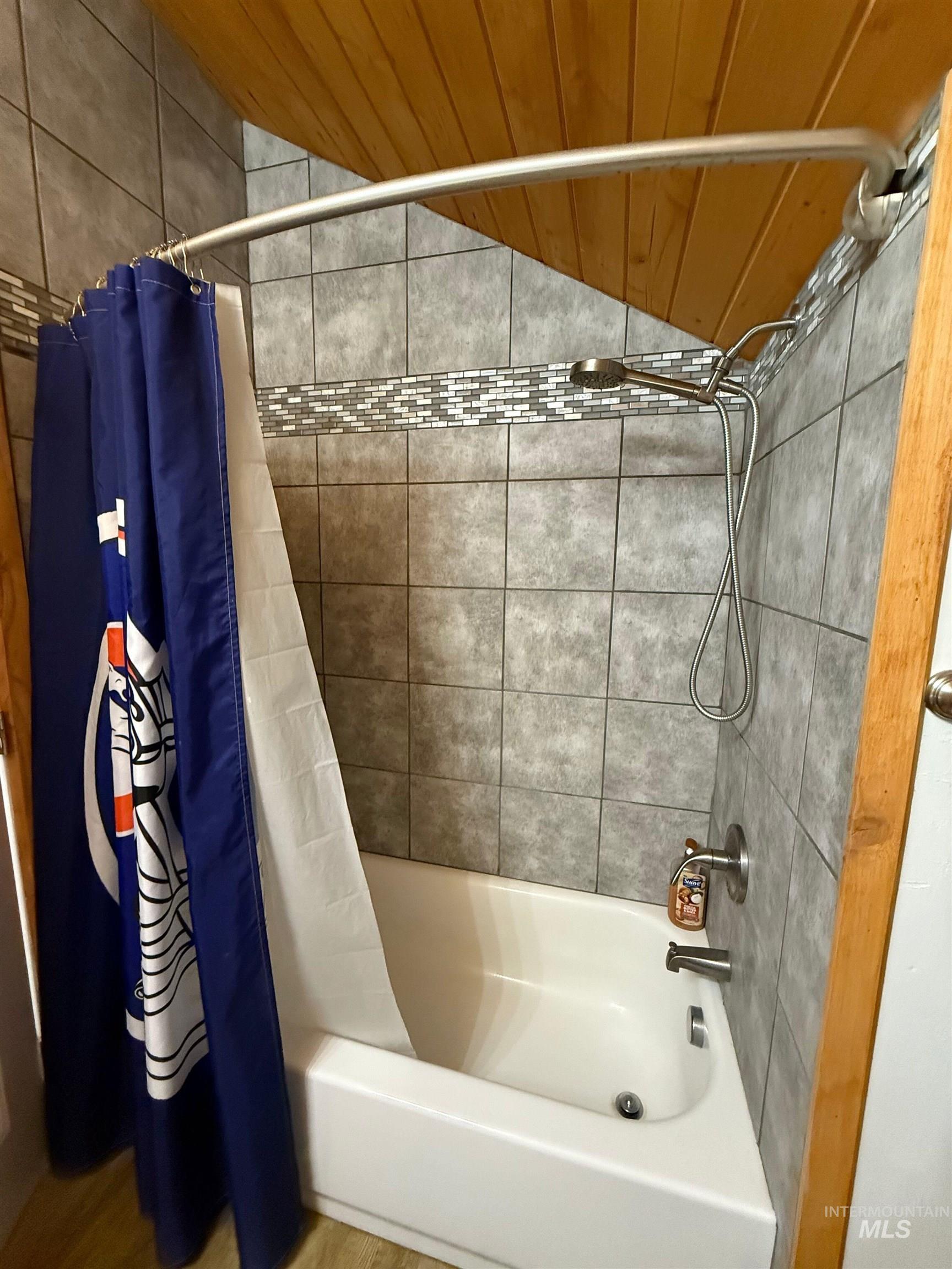 Full bathroom featuring shower / bath combo and lofted ceiling