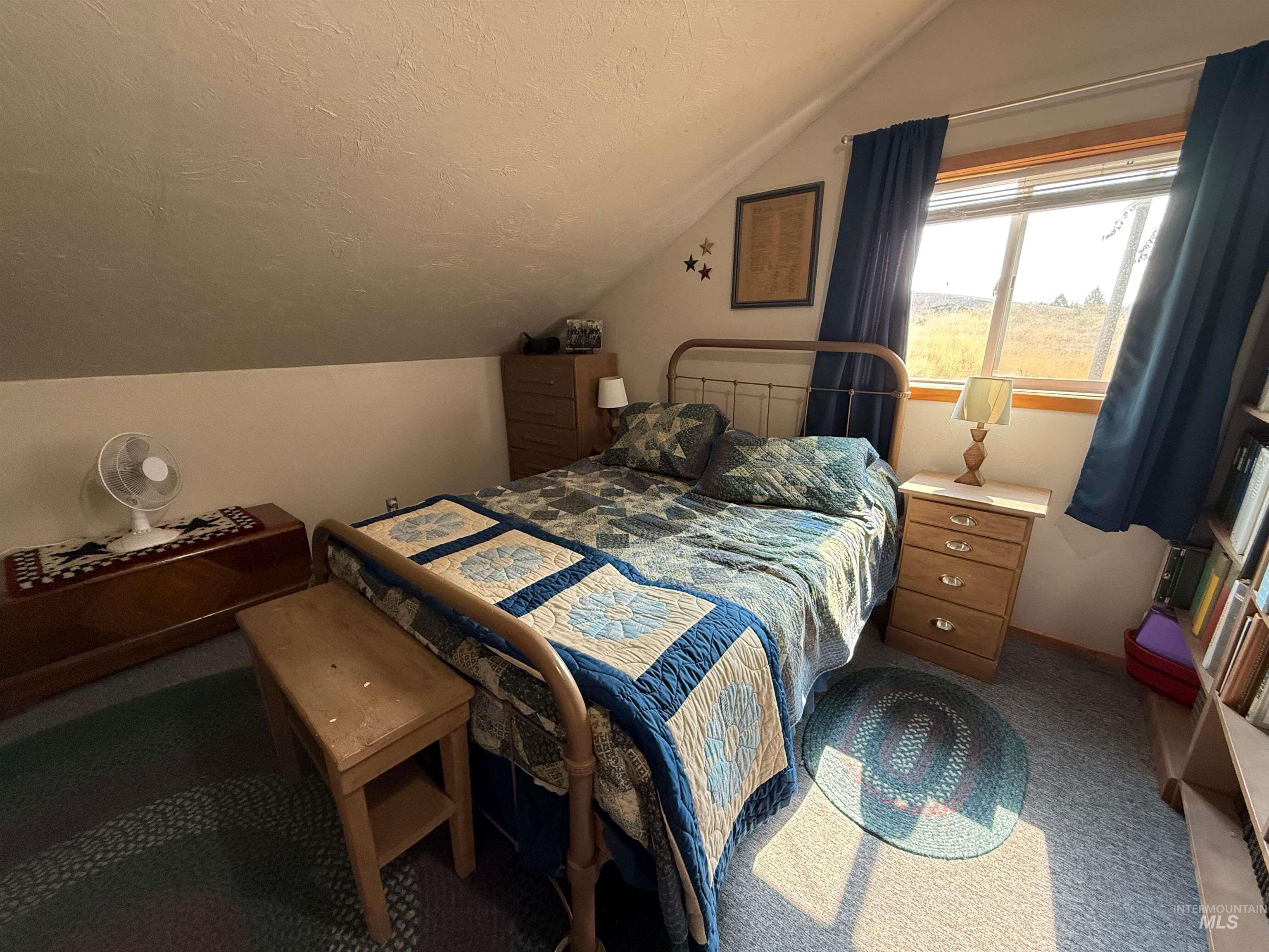 Bedroom with a textured ceiling, vaulted ceiling, and carpet flooring