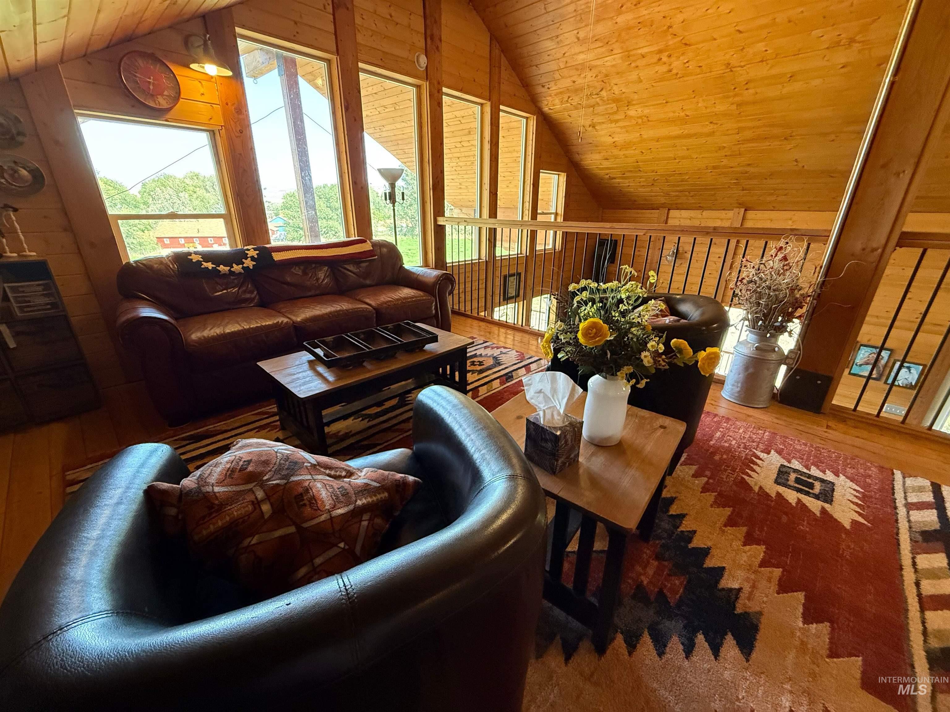 Living room with wooden ceiling, wood finished floors, vaulted ceiling, and wood walls