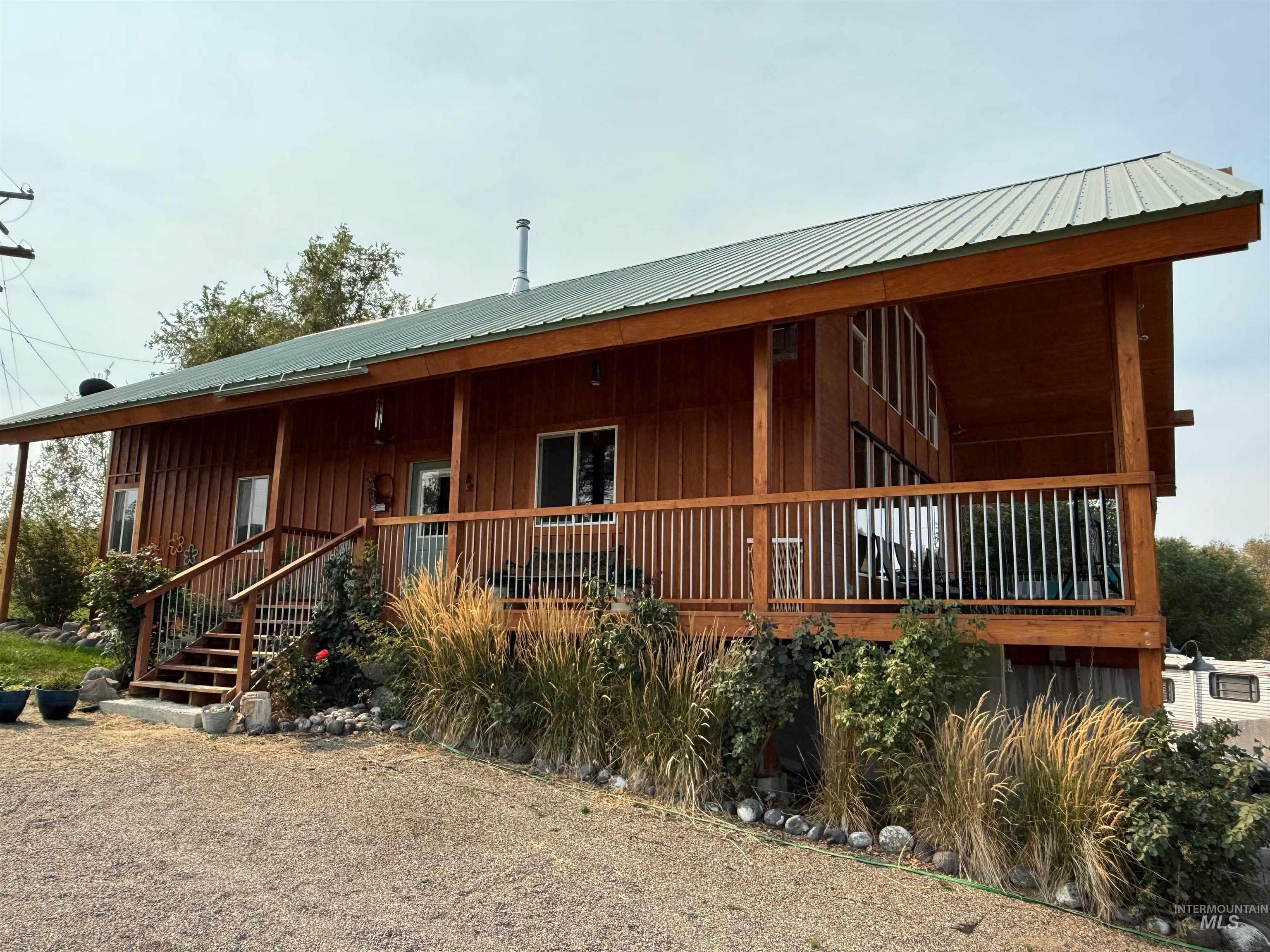 Rear view of house featuring a porch, a metal roof, board and batten siding, and stairway