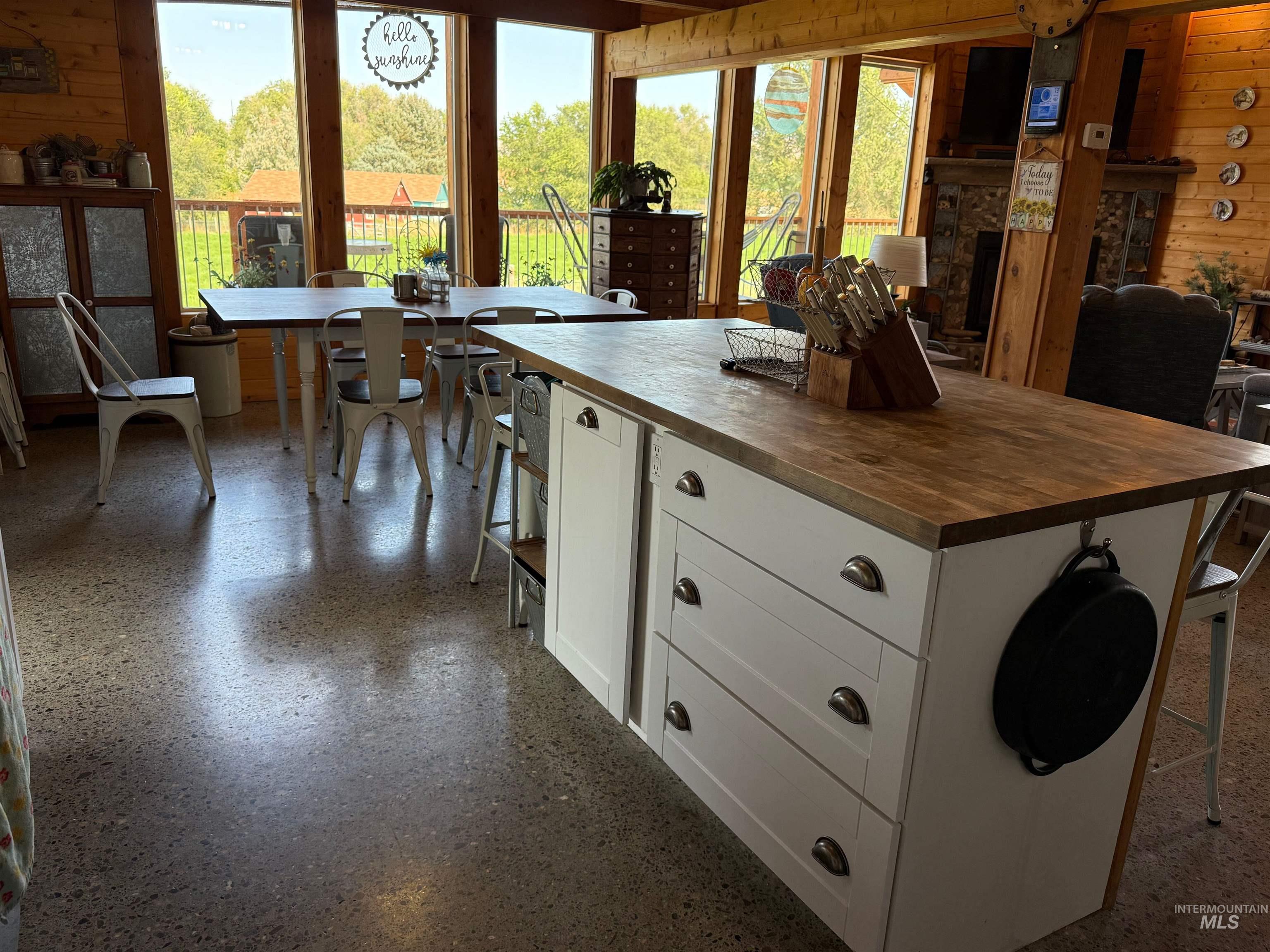 Kitchen with wood walls, white cabinets, butcher block countertops, open floor plan, and a center island