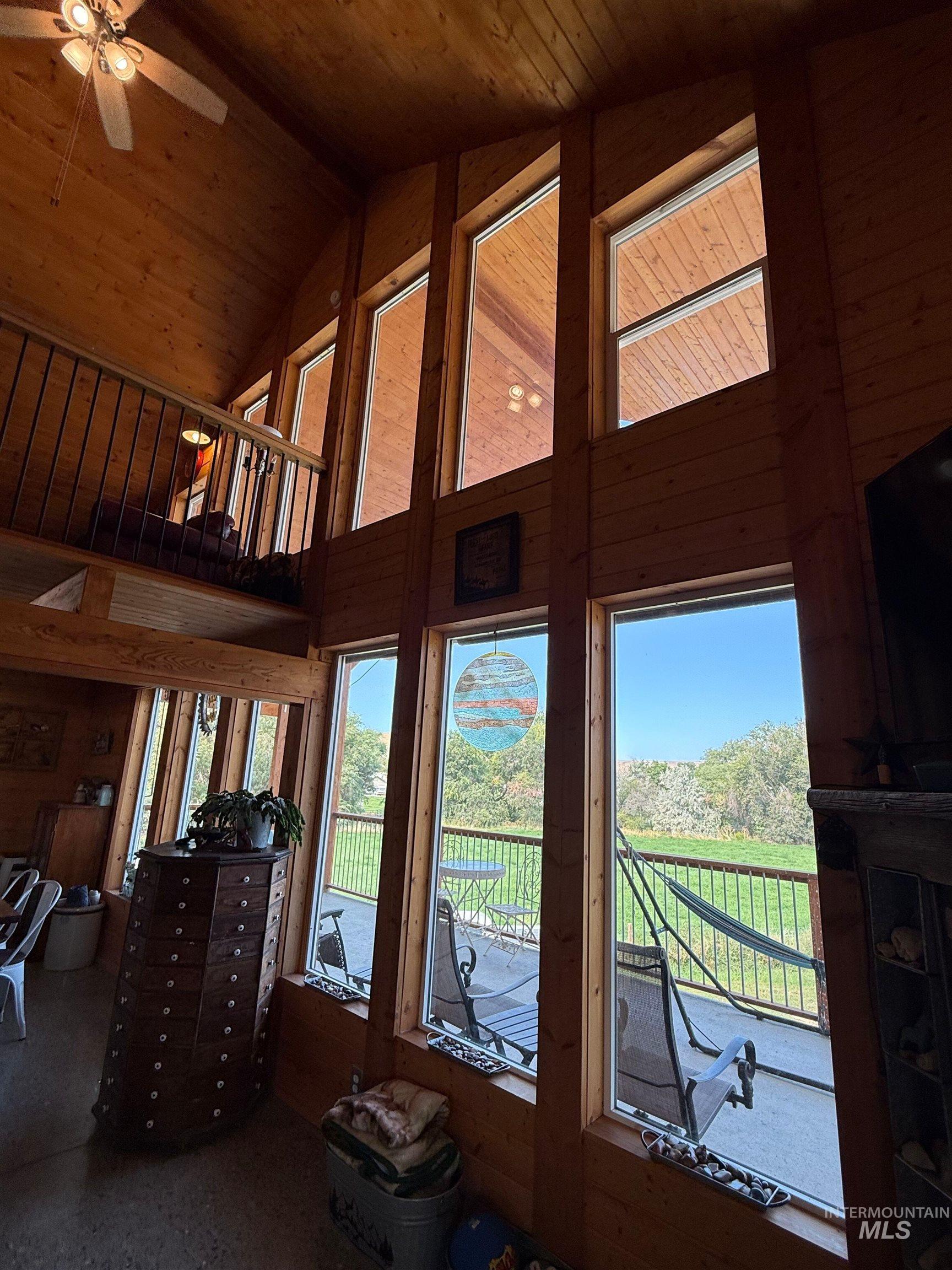 Living room with high vaulted ceiling, wooden walls, wood ceiling, and ceiling fan
