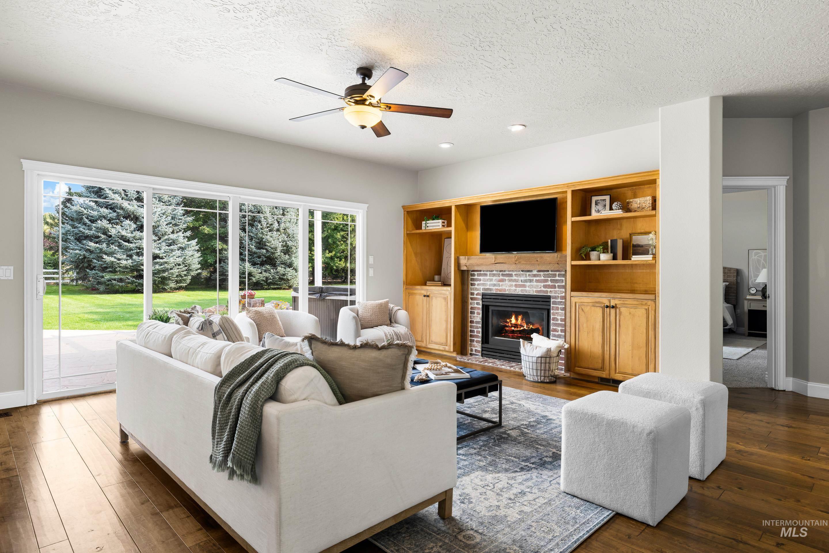 Living area featuring a textured ceiling, a brick fireplace, ceiling fan, dark wood-style floors, and recessed lighting