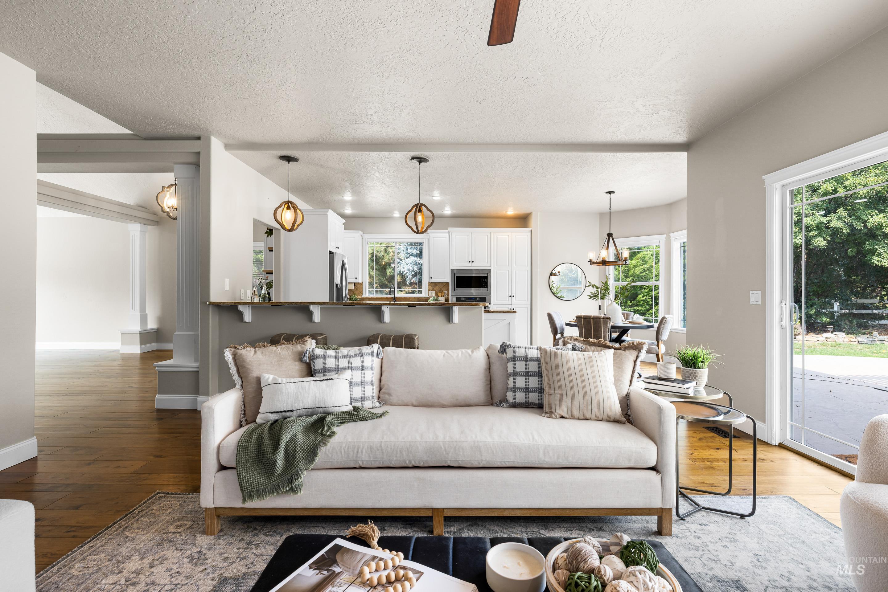 Living room featuring hardwood / wood-style floors, a textured ceiling, a ceiling fan, and a chandelier