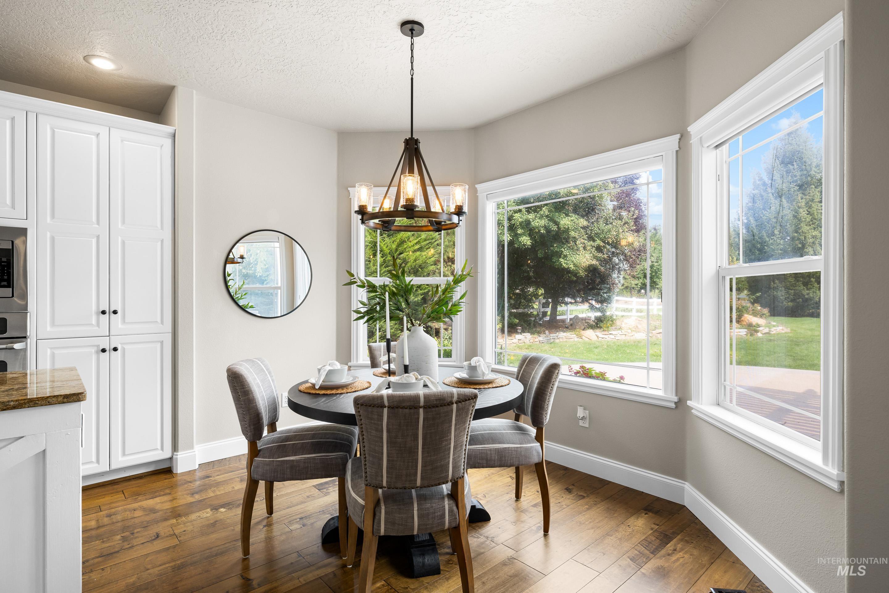 Dining space featuring dark wood finished floors, a chandelier, and a textured ceiling
