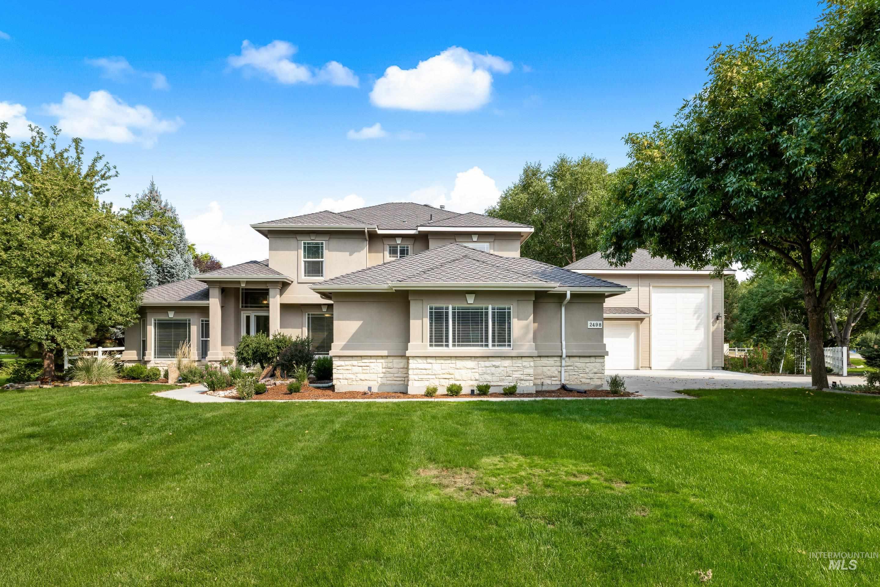 Prairie-style house featuring stucco siding, a front lawn, stone siding, and driveway