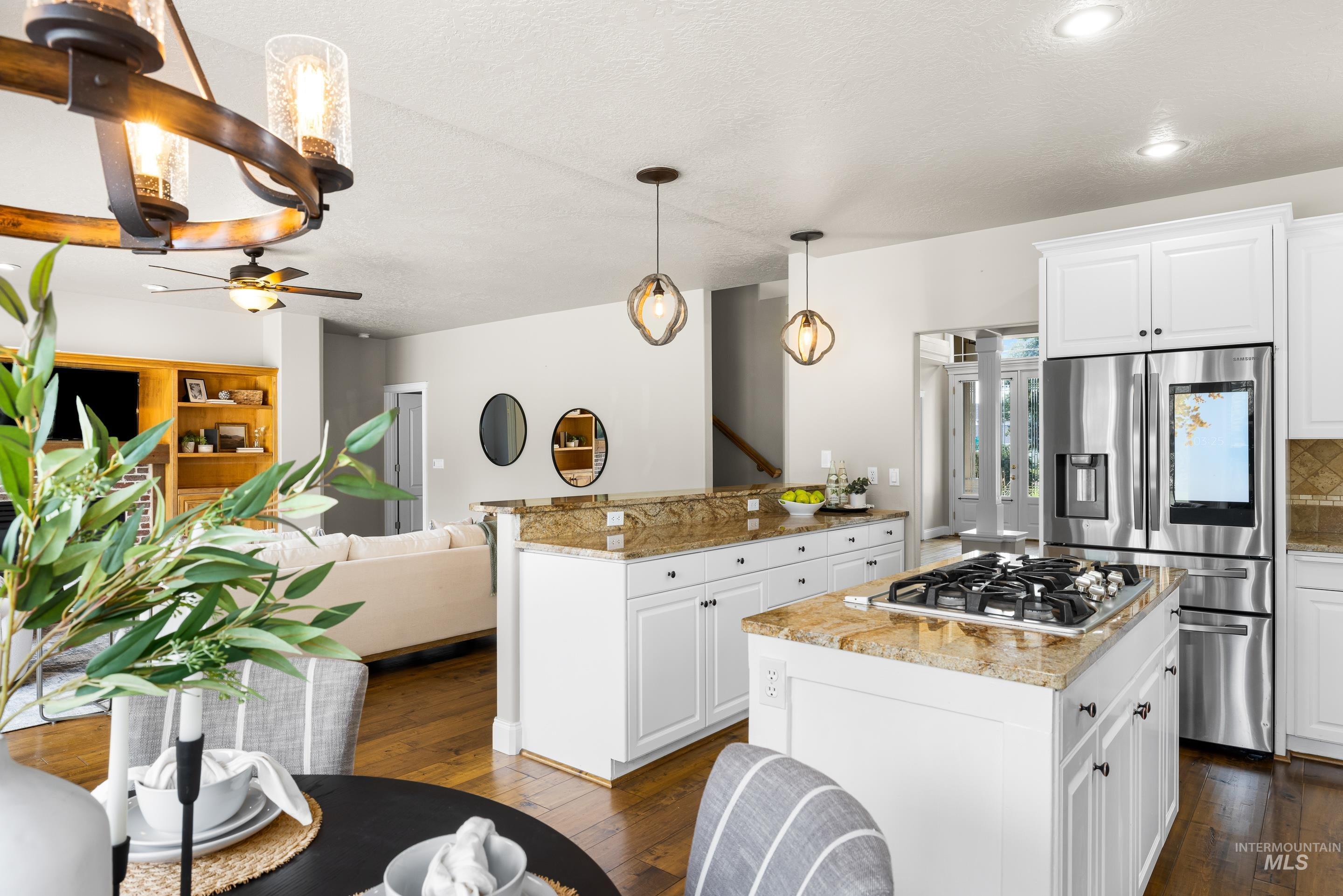 Kitchen with light stone countertops, open floor plan, dark wood-style flooring, white cabinets, and appliances with stainless steel finishes
