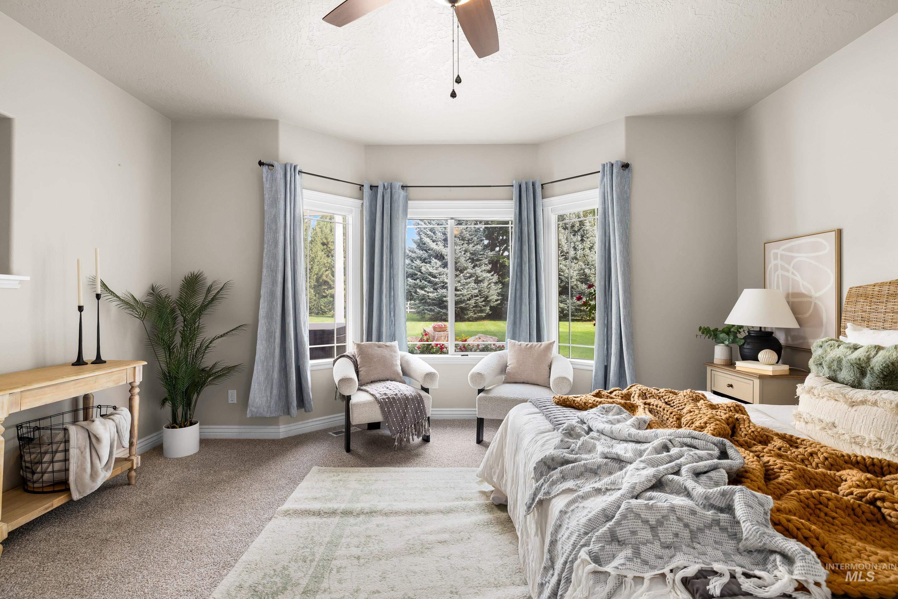 Bedroom with light colored carpet, a textured ceiling, and a ceiling fan