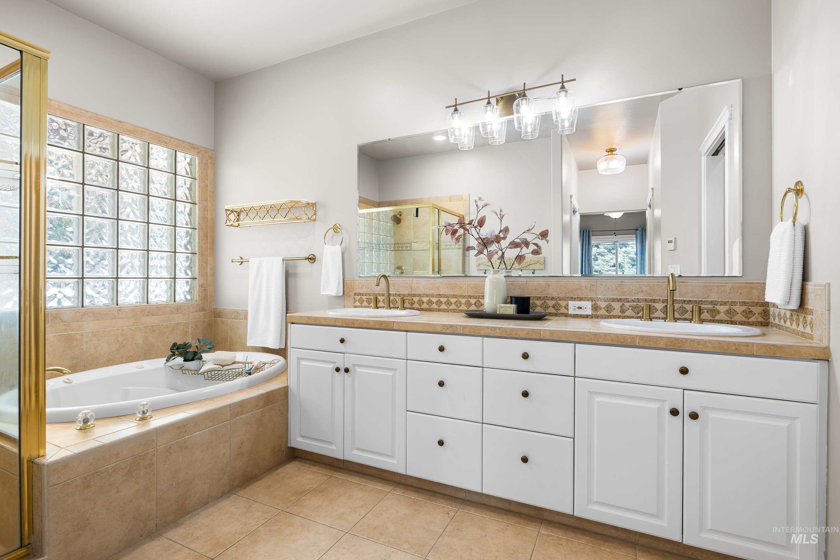 Full bathroom featuring a shower stall, double vanity, a bath, and light tile patterned floors