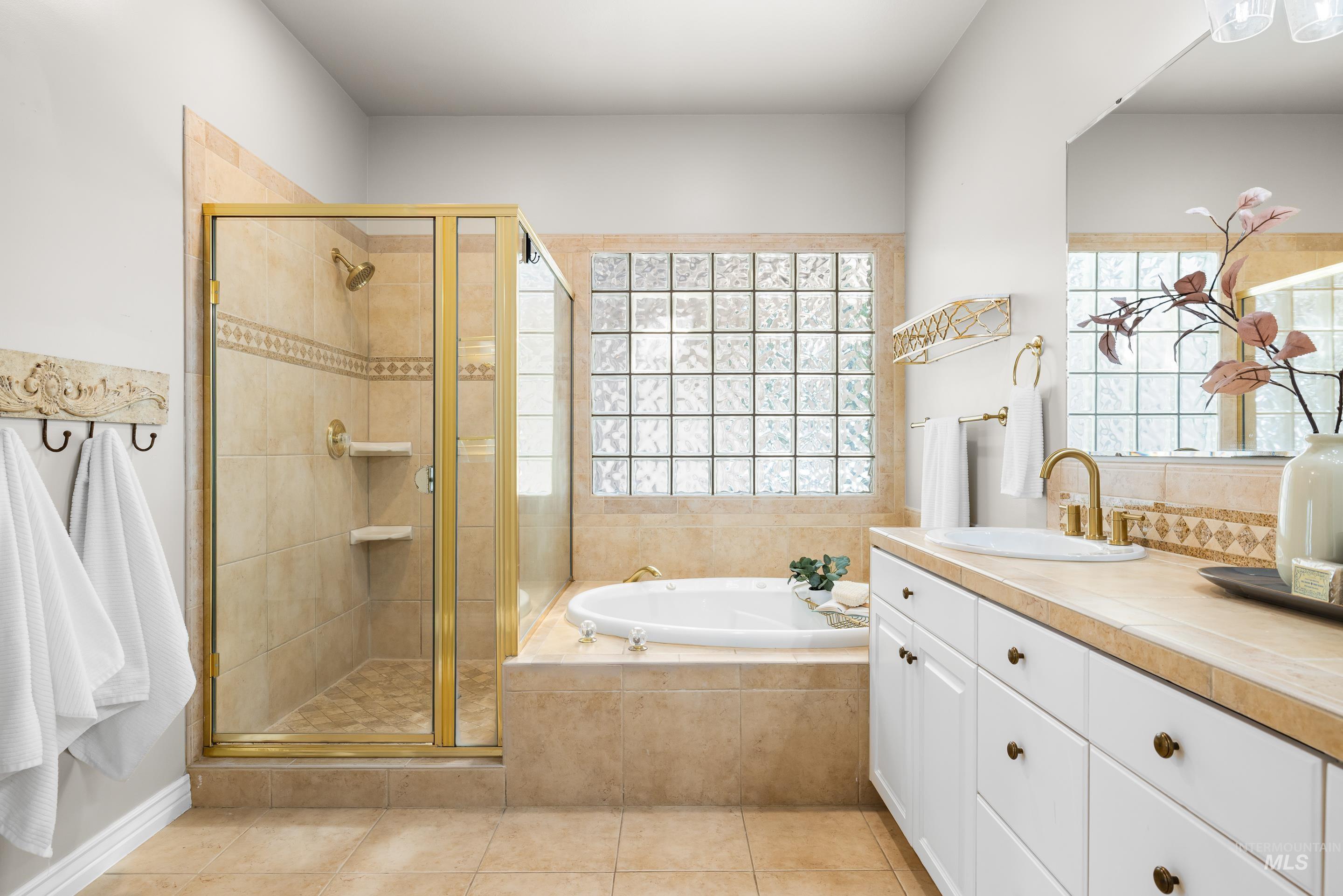 Bathroom featuring a garden tub, a shower stall, vanity, and light tile patterned floors