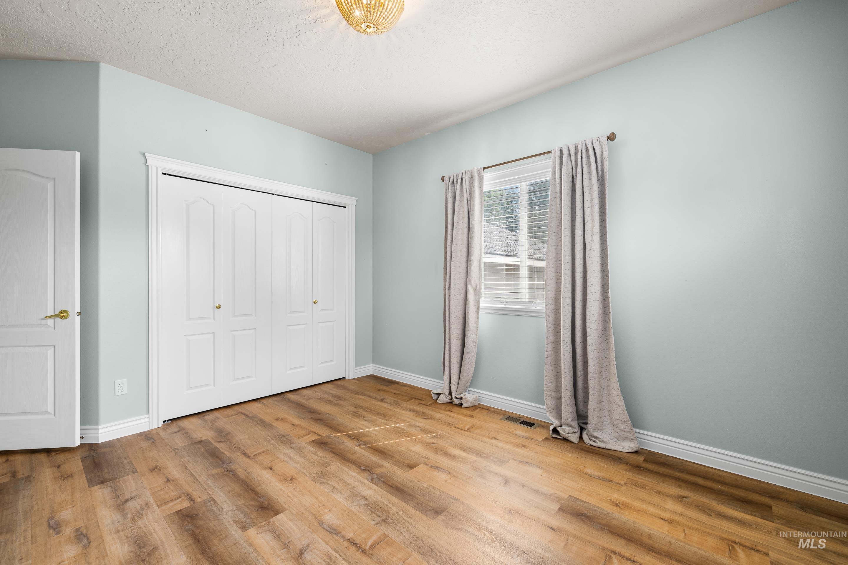 Unfurnished bedroom featuring a closet, light wood finished floors, and a textured ceiling