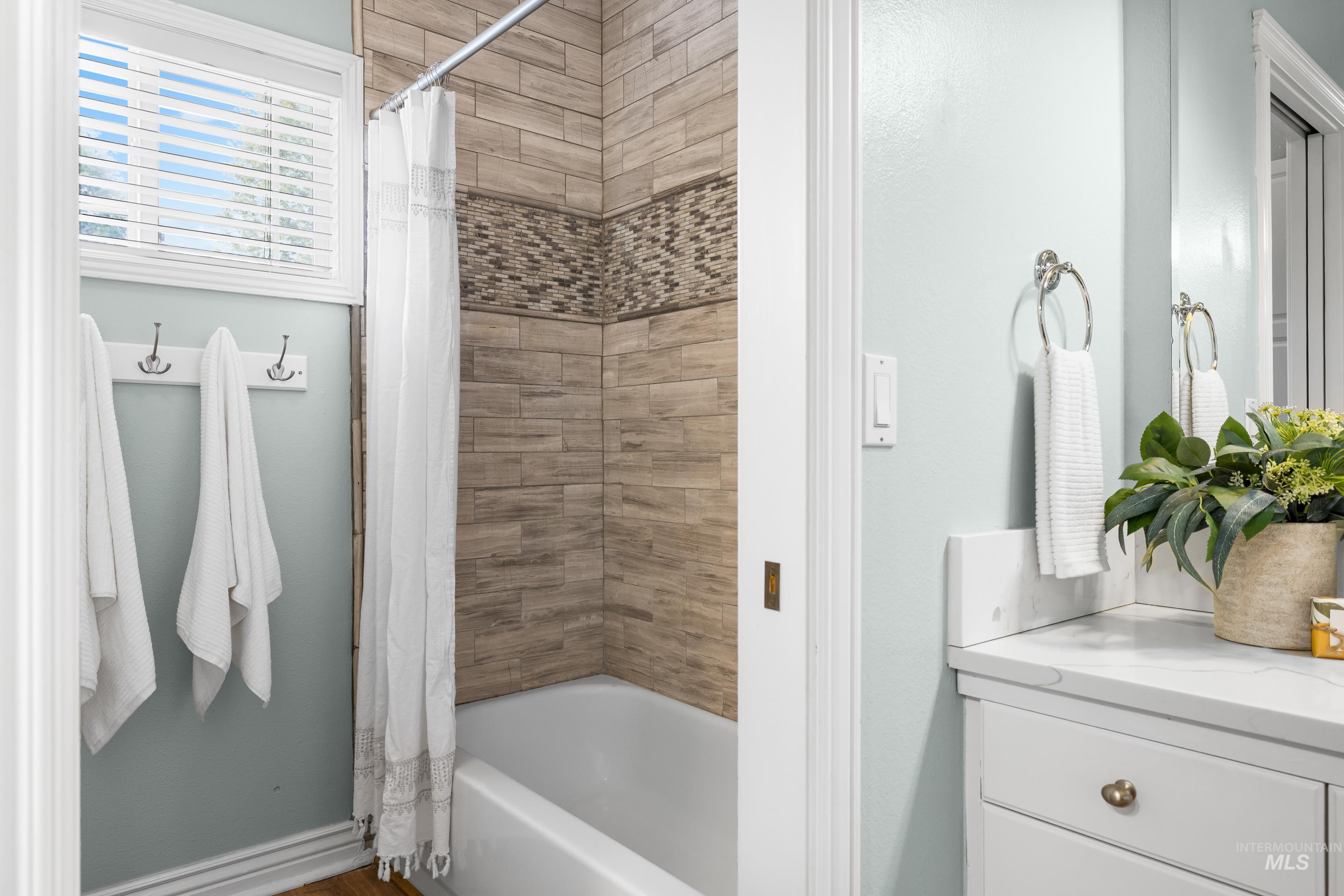 Full bath with shower / tub combo with curtain and vanity