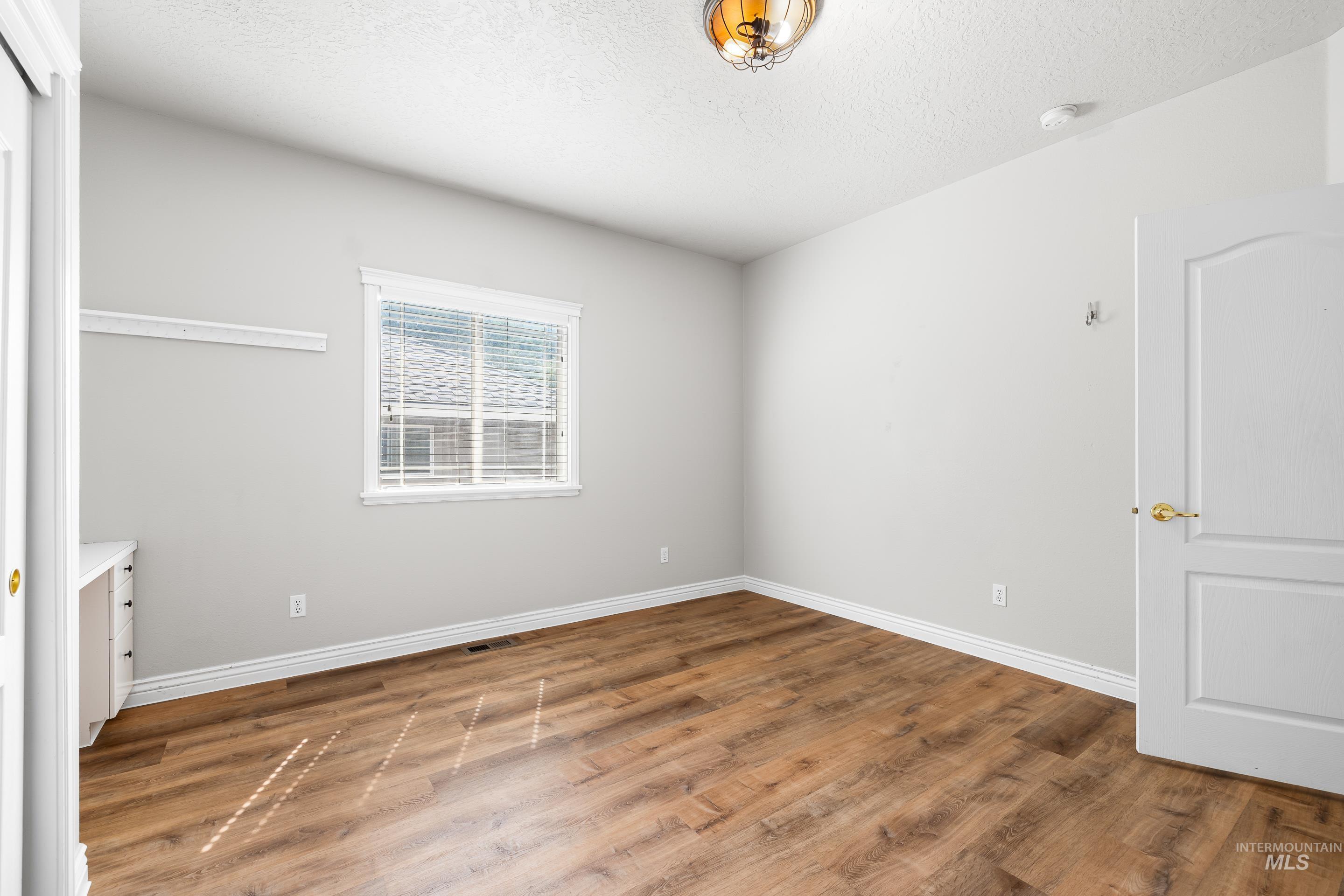 Unfurnished bedroom featuring wood finished floors and a textured ceiling