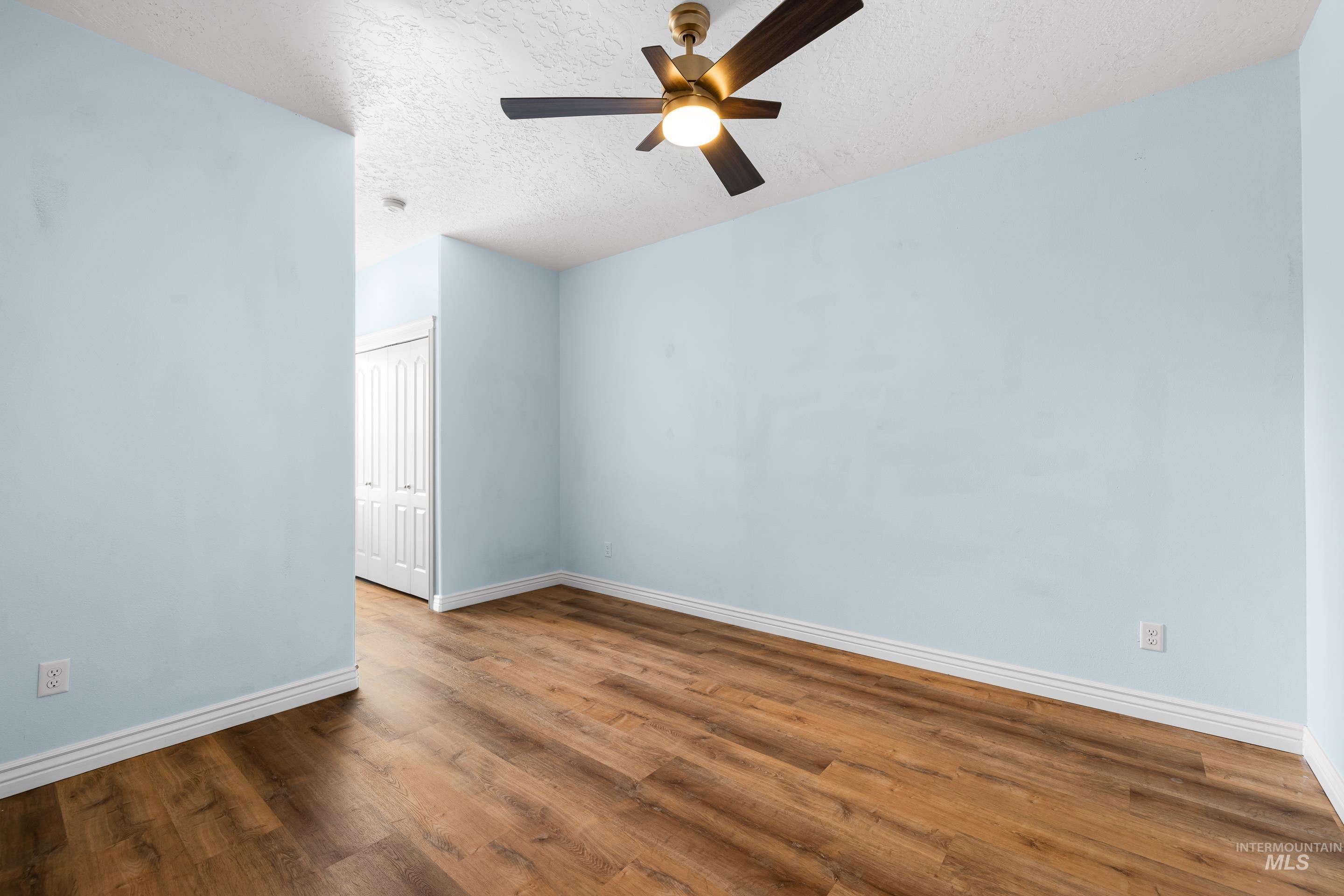 Unfurnished room with wood finished floors, a textured ceiling, and ceiling fan