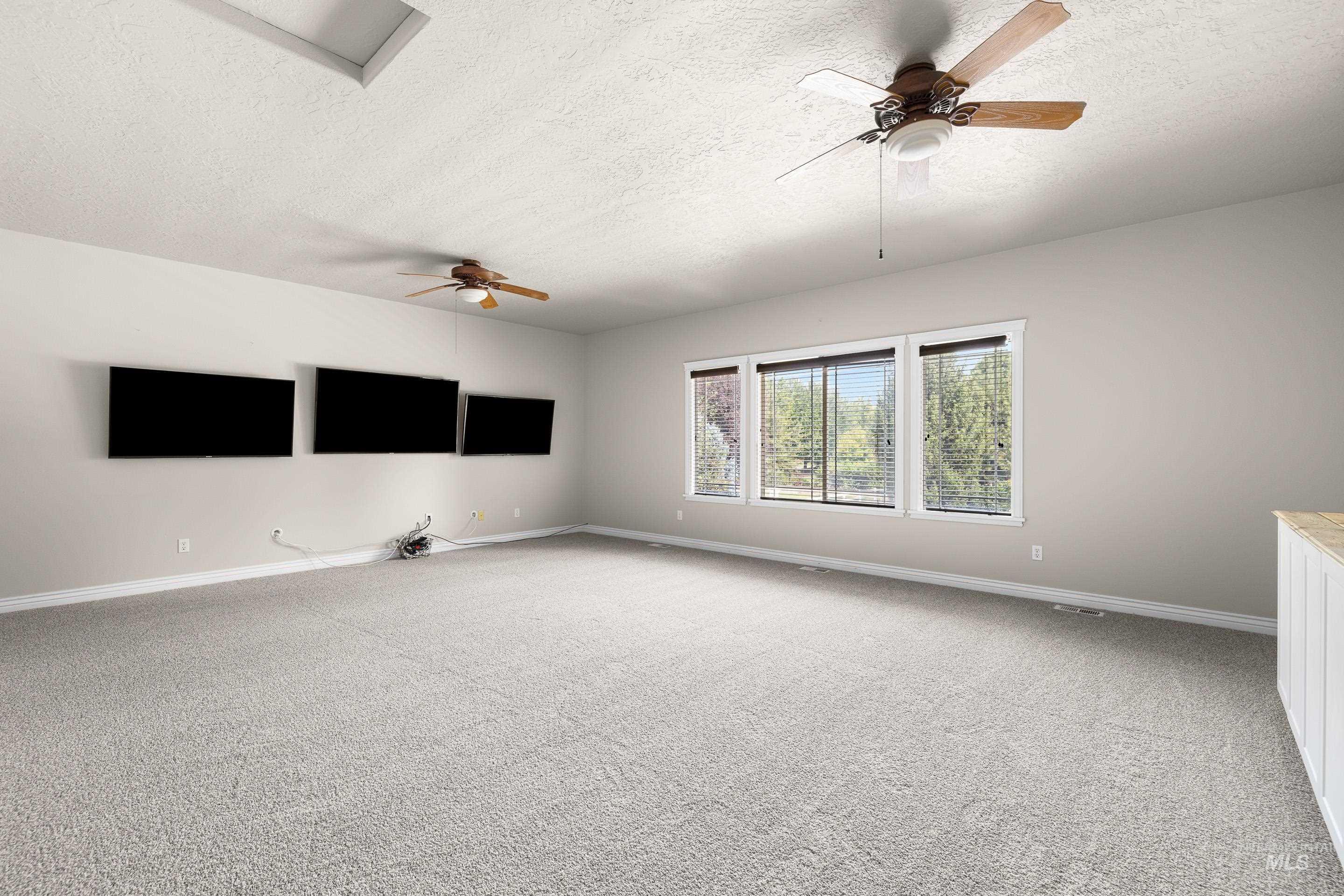 Unfurnished room featuring a ceiling fan, a textured ceiling, and light carpet