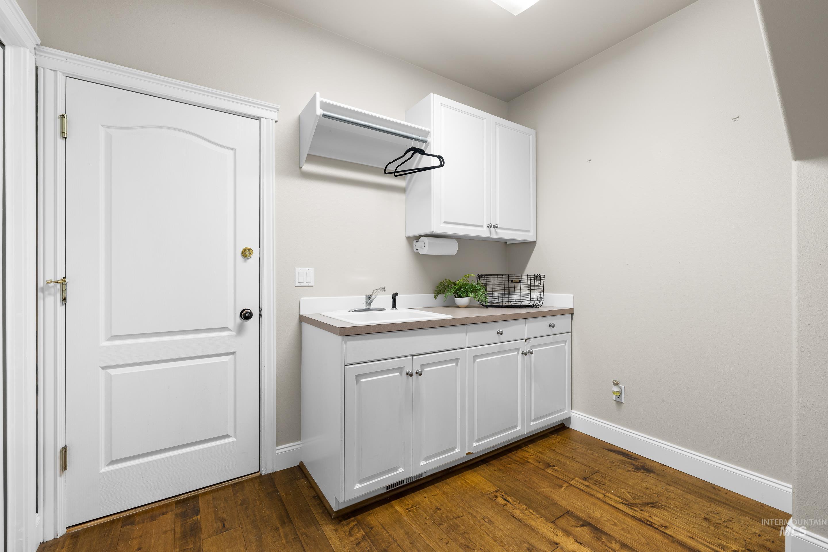 Laundry area featuring baseboards and dark wood-type flooring