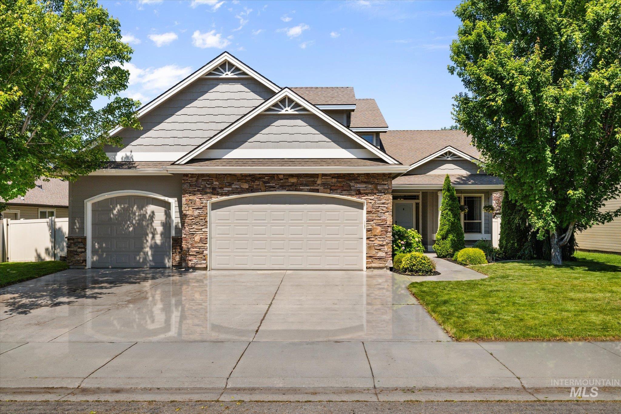 Craftsman-style home featuring driveway, stone siding, and a garage