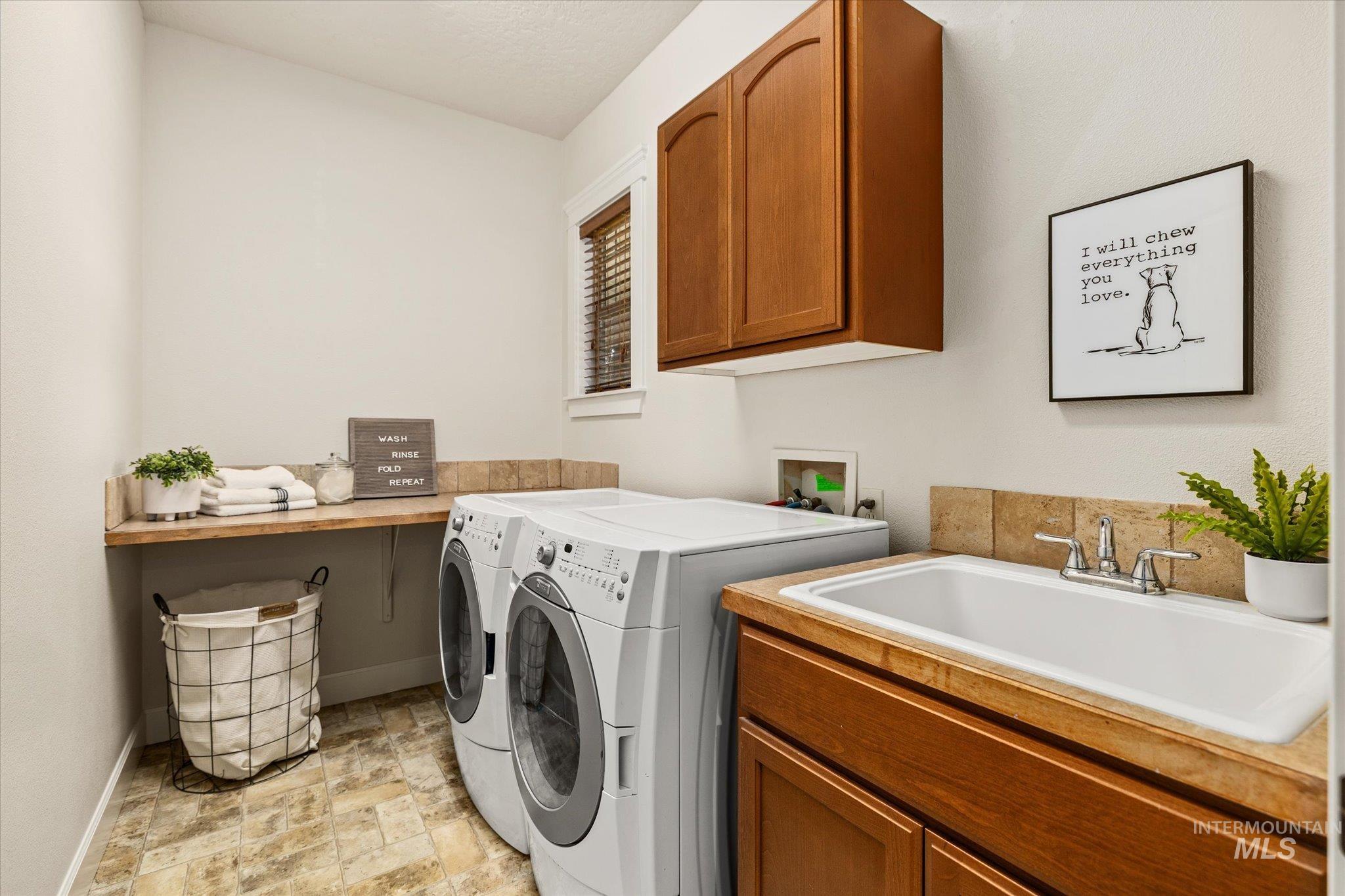 Laundry room featuring washer and dryer, stone finish floors, and cabinet space