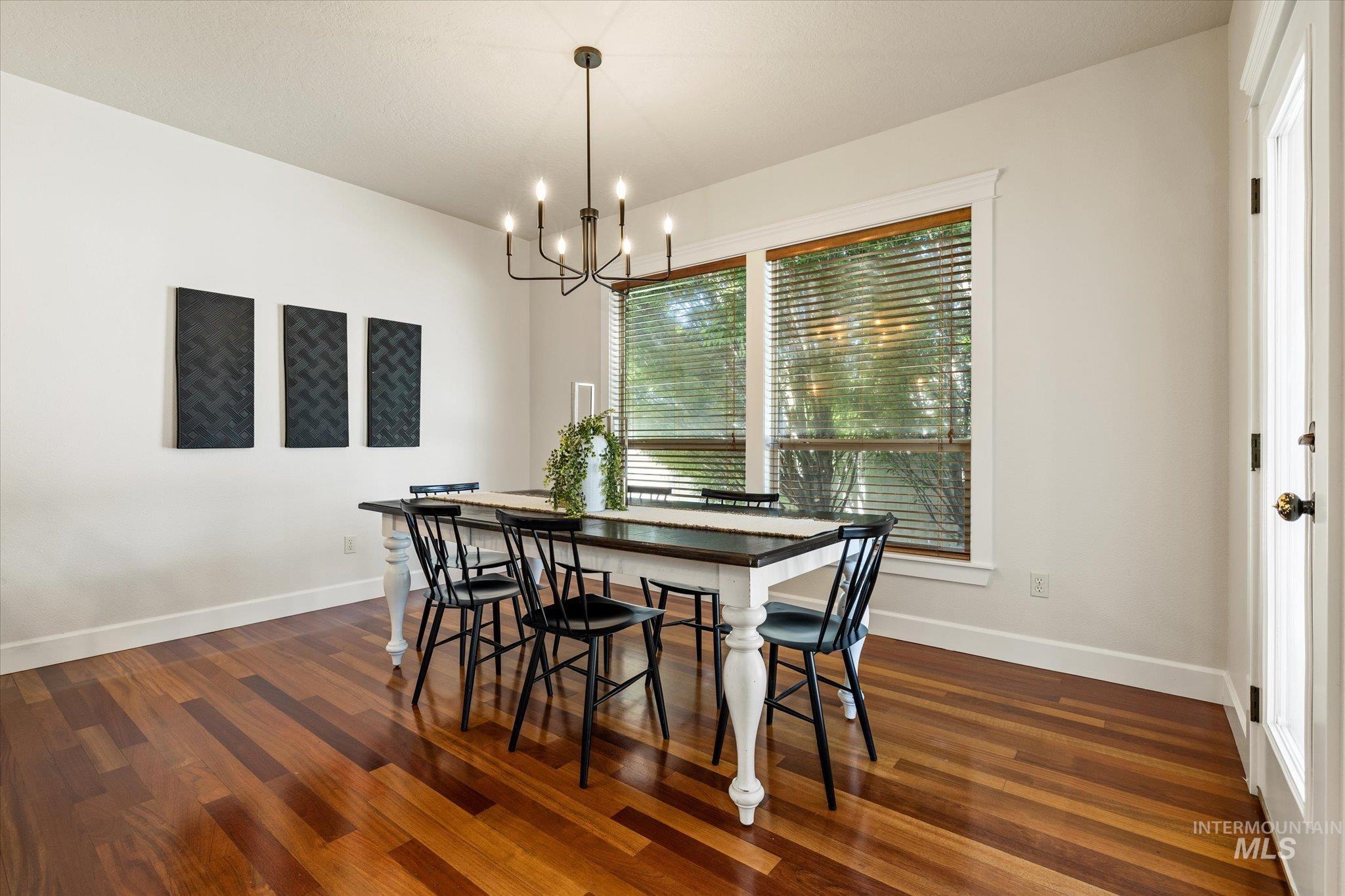 Dining space featuring dark wood-style flooring and a chandelier