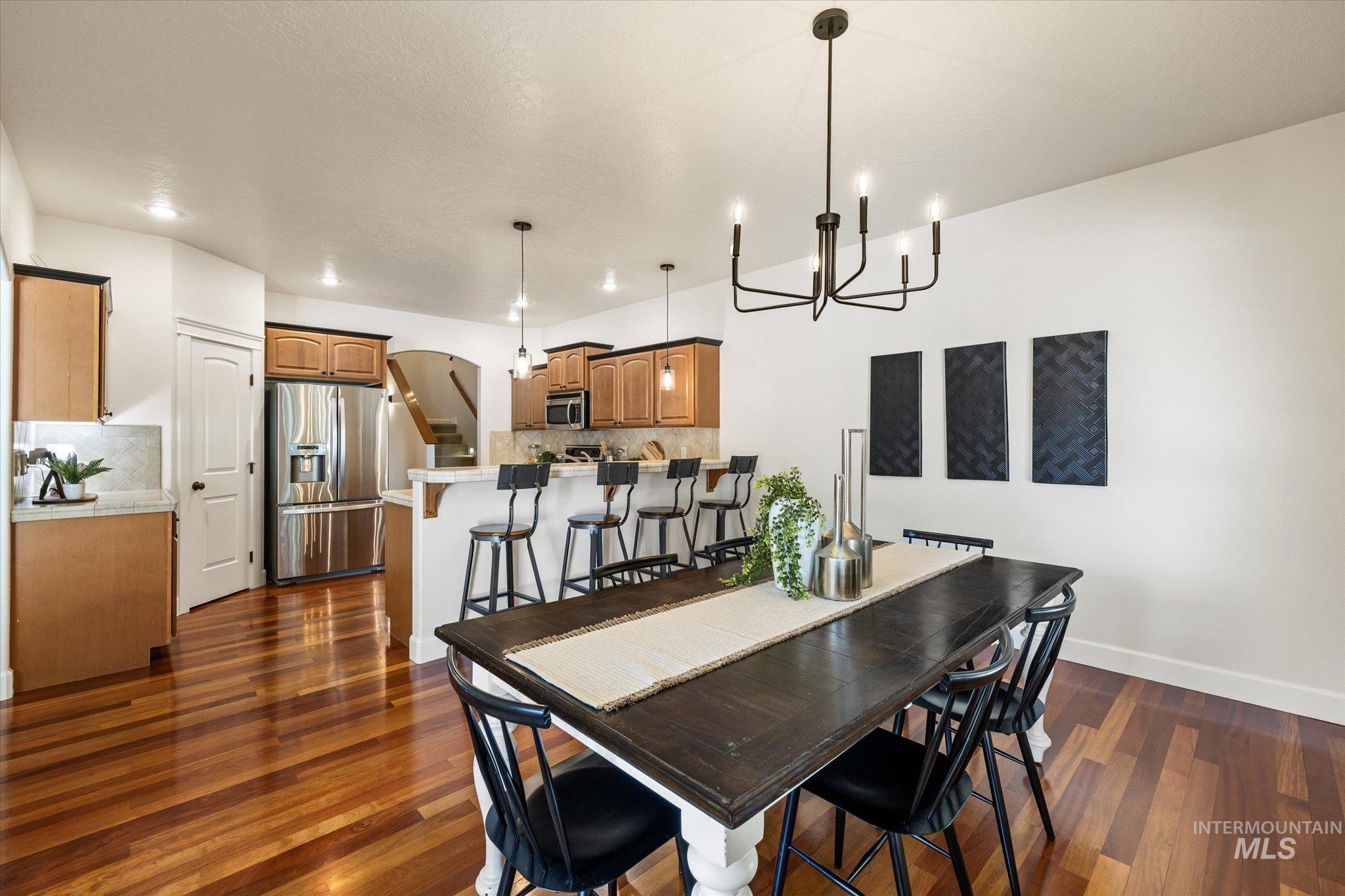 Dining room with a chandelier, dark wood-type flooring, and arched walkways