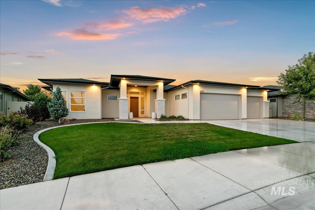 Prairie-style home featuring stucco siding, concrete driveway, an attached garage, and a front yard